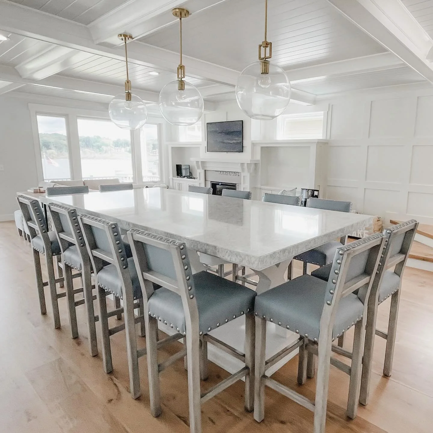 Designed for gathering. 🌊

This built-in counter height table brings casual coastal style and everyday function together &mdash; paired with light blue performance leather stools finished with oversized hammered nail detail for a fun, relaxed look m