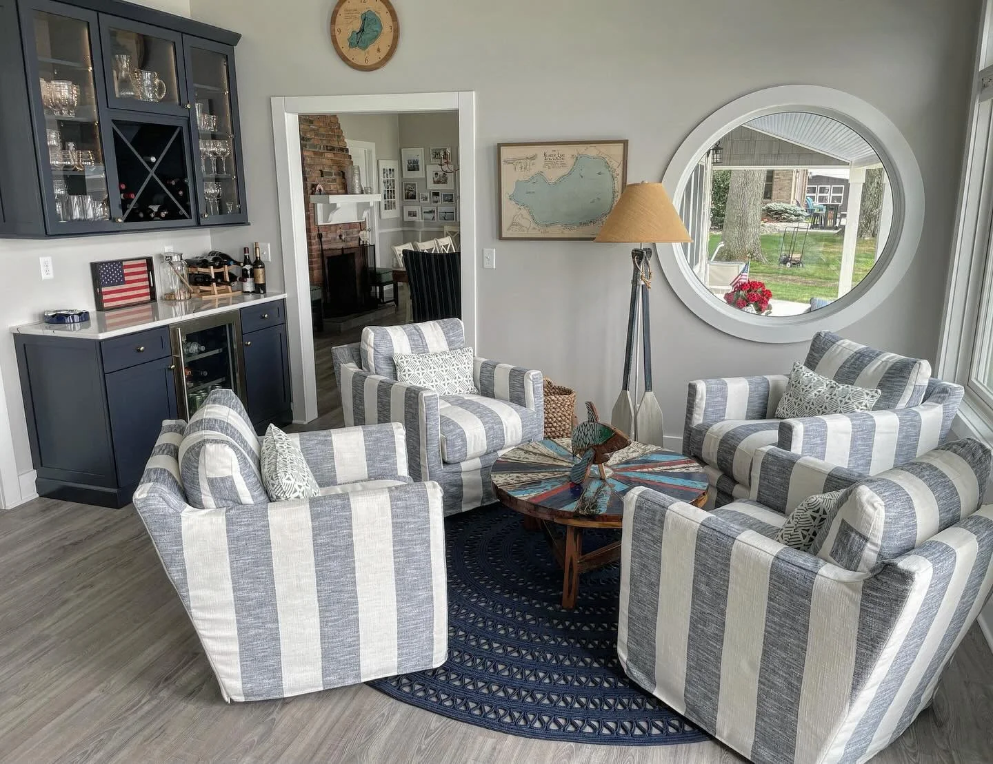This cozy conversation space was designed for slow mornings, cocktail hours, and long summer nights &mdash; featuring four swivel lounge chairs in classic navy + white stripe surrounding a fun reclaimed boat cocktail table.  Also featuring a custom b