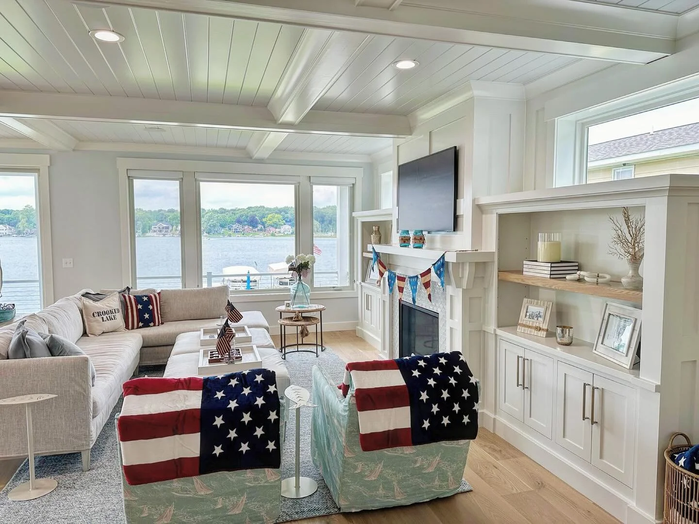 Red, white &amp; lake views. 🇺🇸
A cozy holiday-ready living room designed for gathering, relaxing, and soaking in summer by the water.

From lake houses to coastal homes, we love creating spaces that feel collected, comfortable, and lived in. ❤️

#