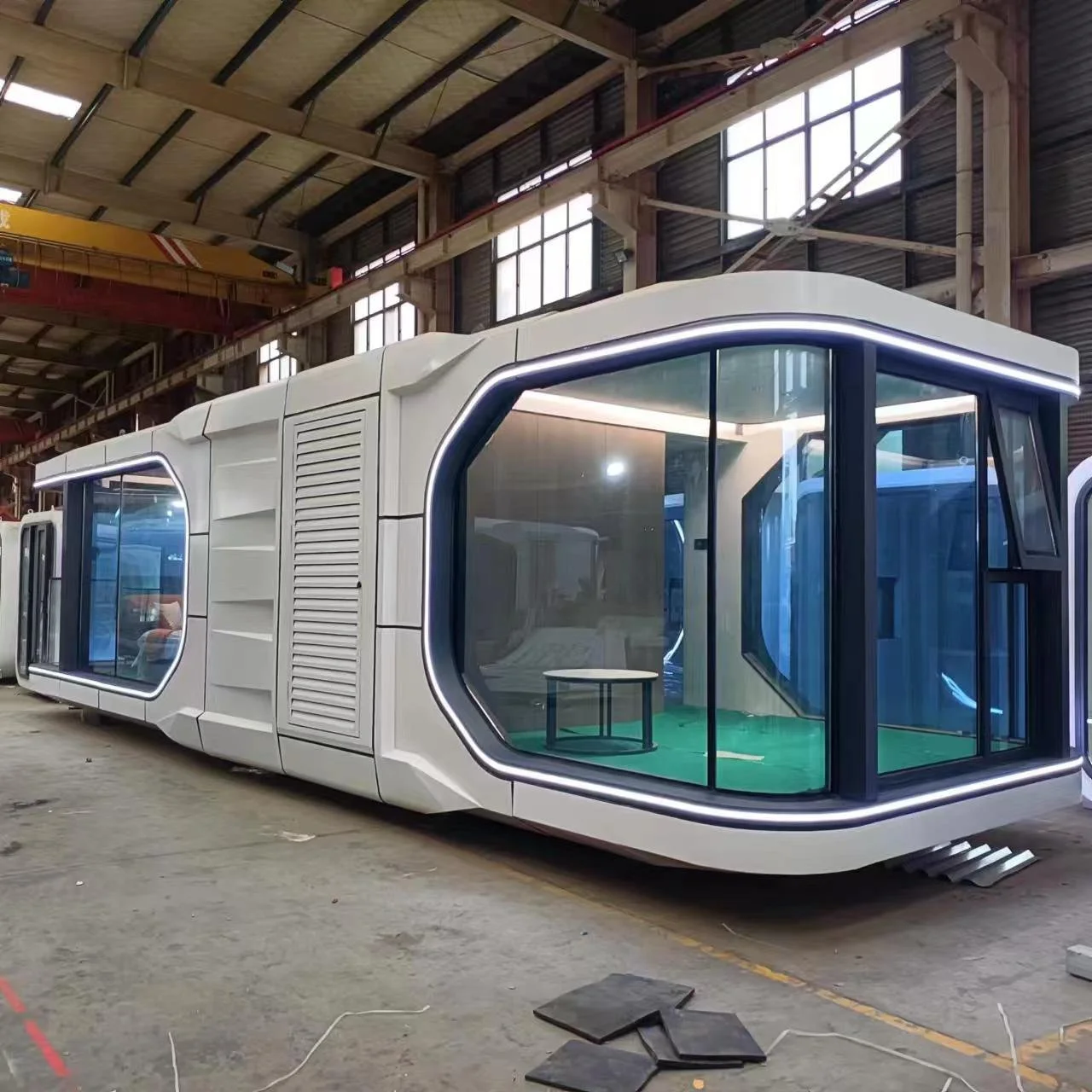 Futuristic modular building with large glass windows and white exterior inside a warehouse.