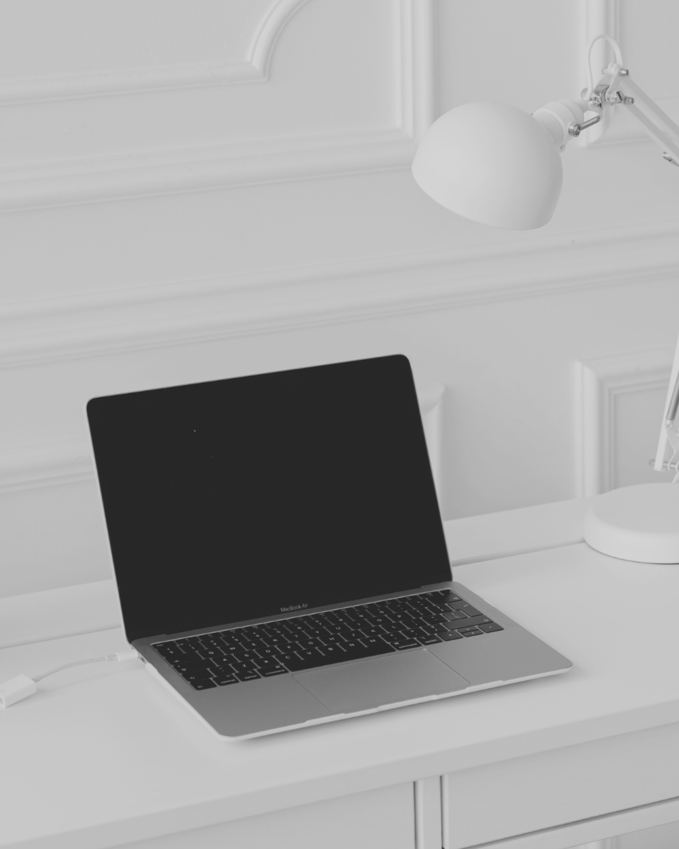 Minimal white desk with a laptop and lamp
