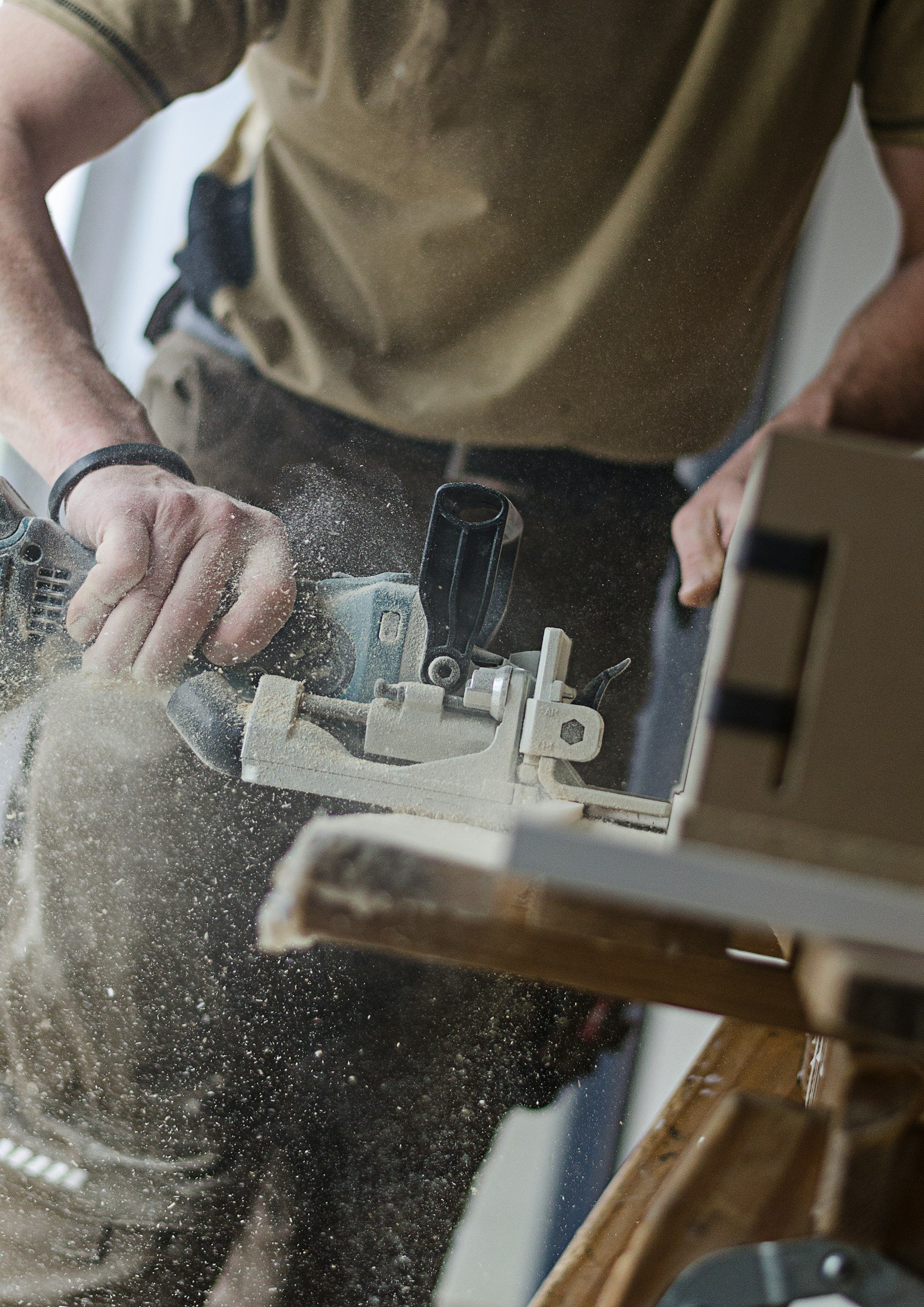Person using a power saw to cut wood, with sawdust flying in the air.