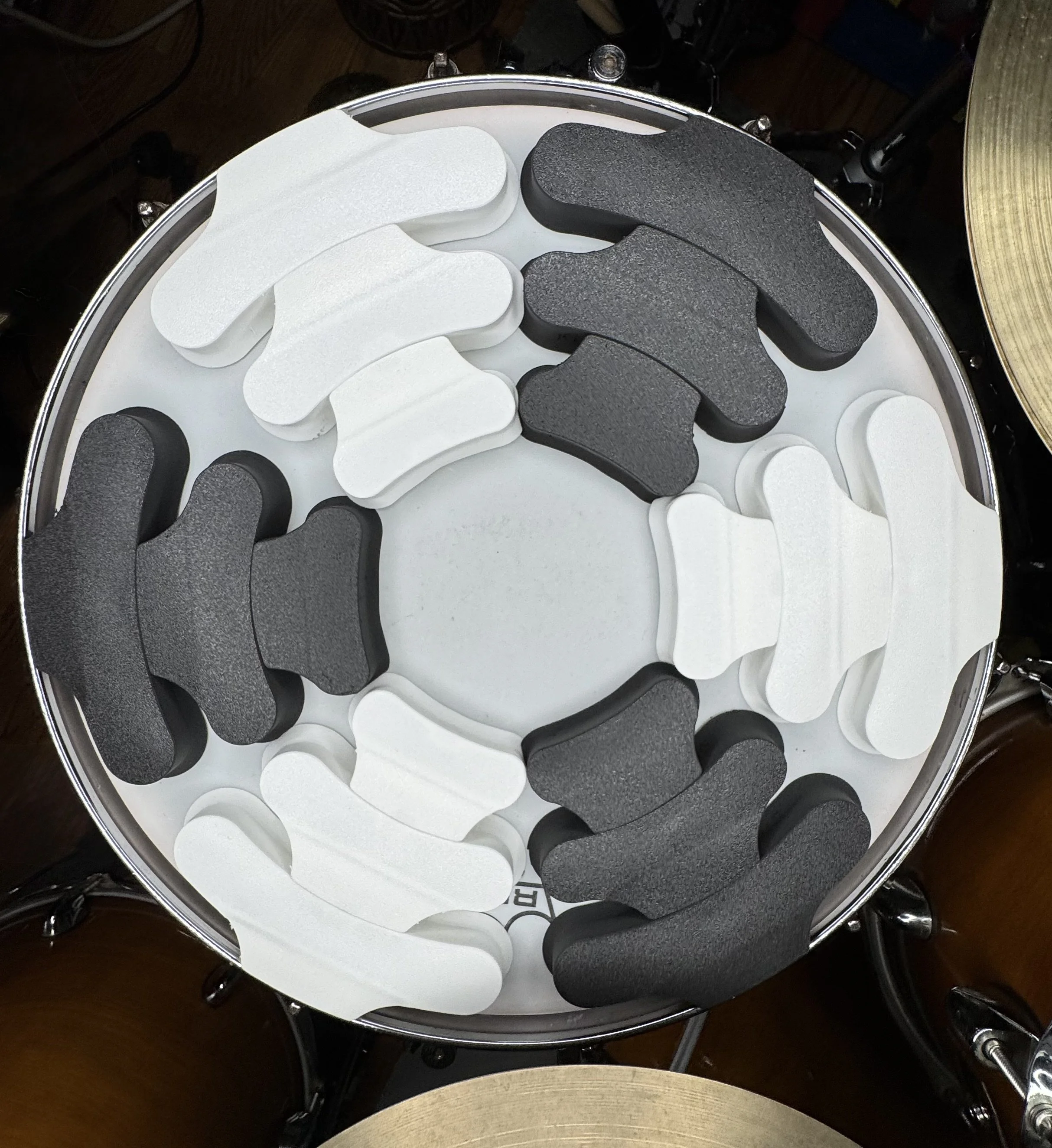 Close-up view of a drum set cymbal with various black and white drum mufflers arranged in a circle on top.