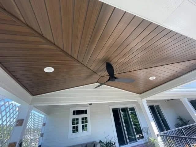 Wood-paneled ceiling with a ceiling fan, recessed lighting, and sliding glass doors leading outside.