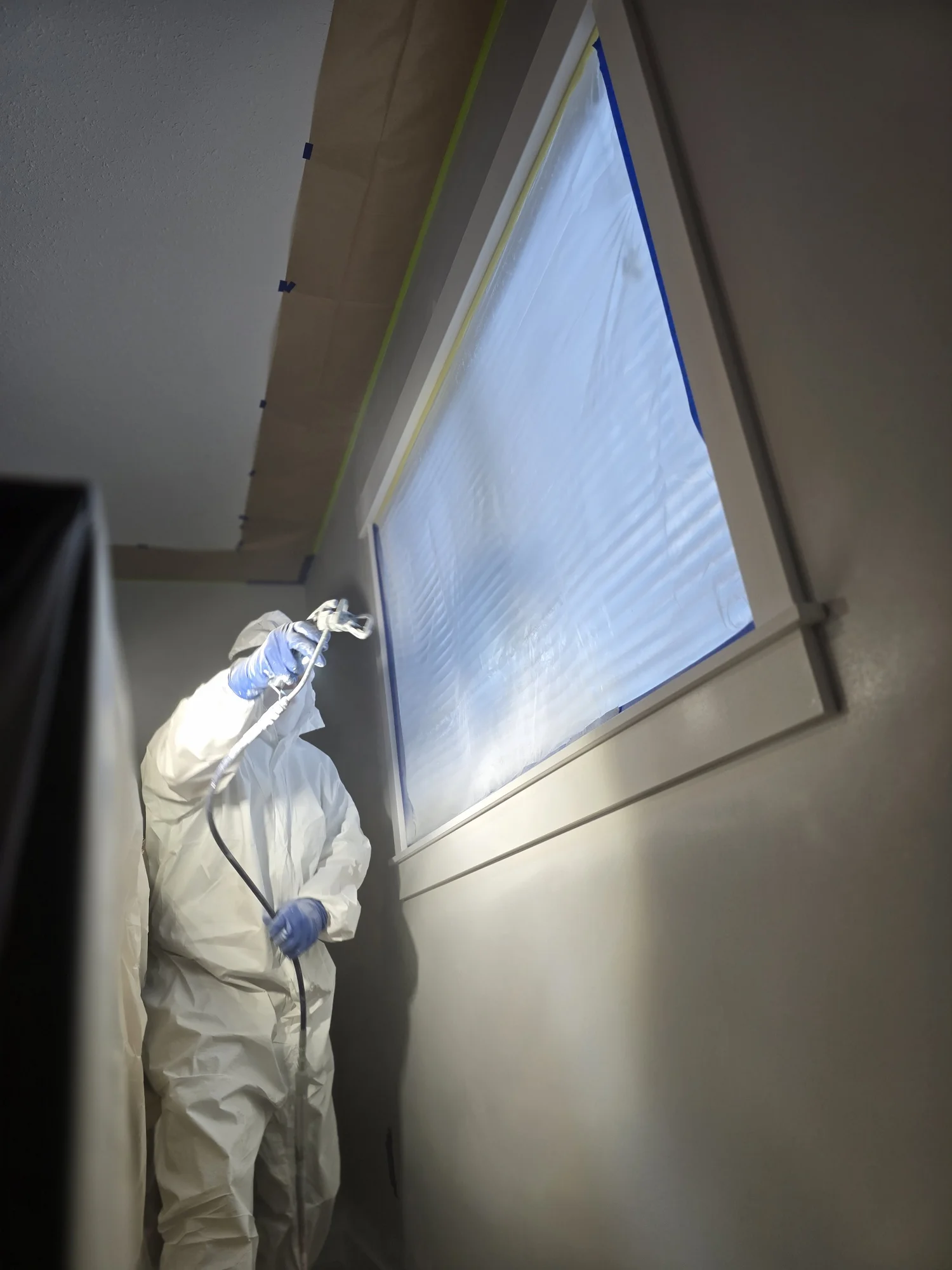 Nick’s Paint Works painting an interior beside a masked window