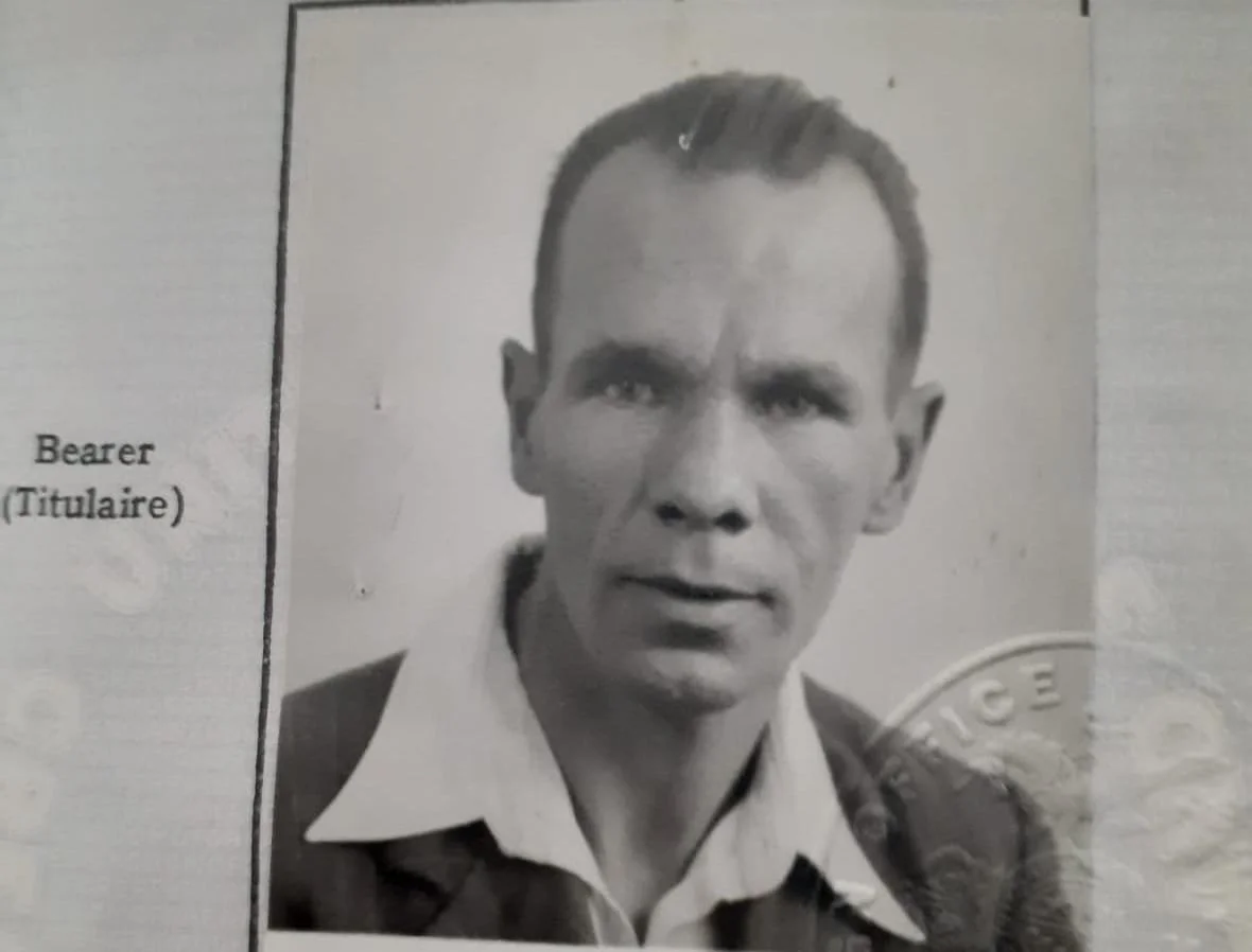 Black and white photograph of a man with short, slicked-back hair, wearing a collared shirt, with a police badge partially visible on the right side of the image.