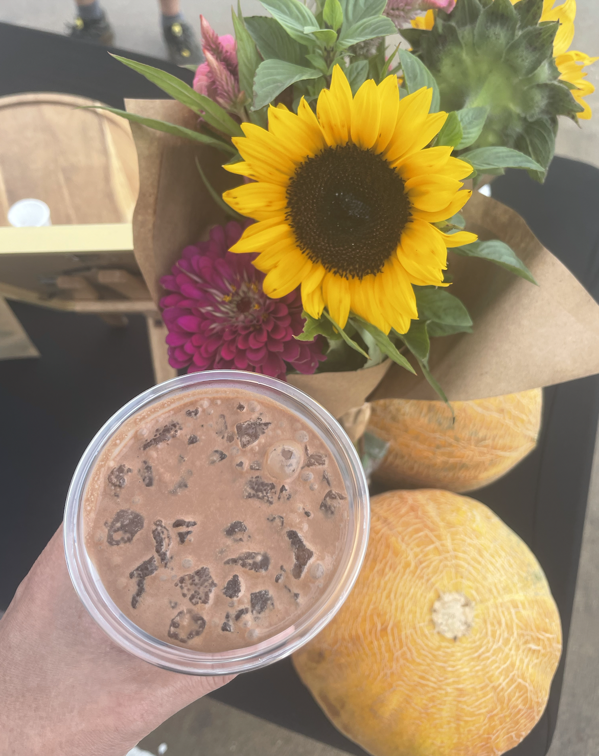 a cup of iced cacao with farmers market melons and sunflower