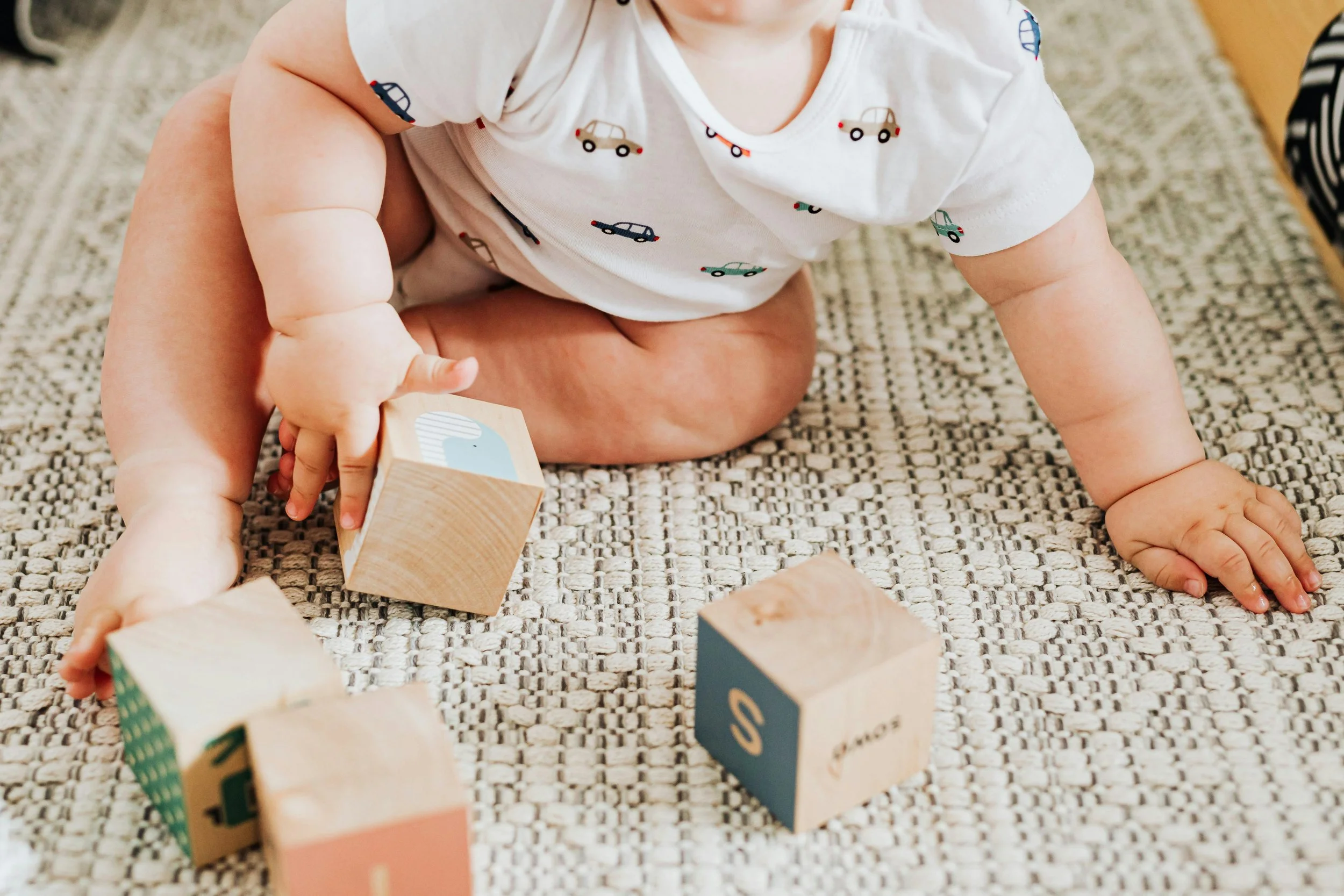 baby playing with wooden montessori blocks independent floor time gross motor and fine motor development and milestones supported by parent consulting