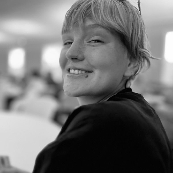 Black and white photo of Aria McGowan, Undefined Wellness Founder smiling sitting in an indoor space.