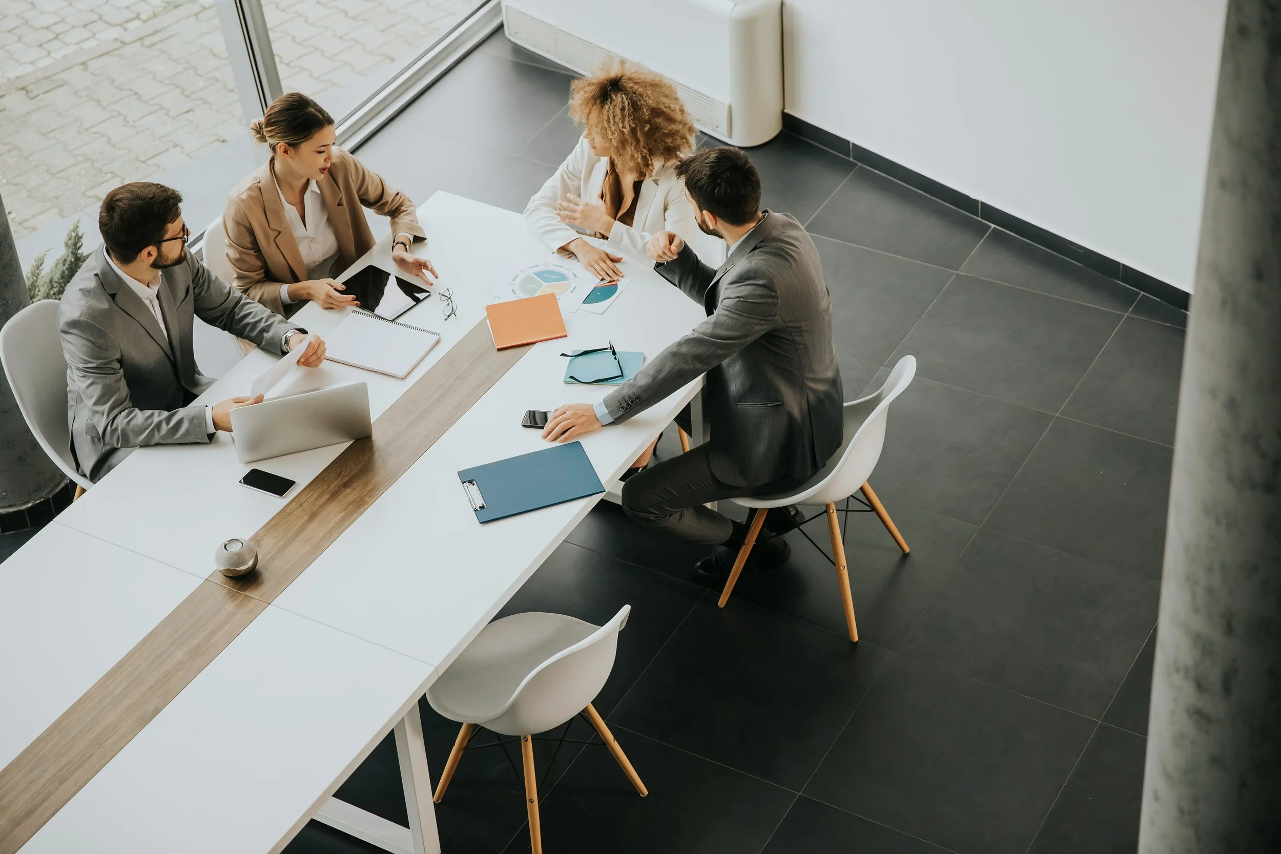 A group of five business professionals in a meeting around a table in a modern office.