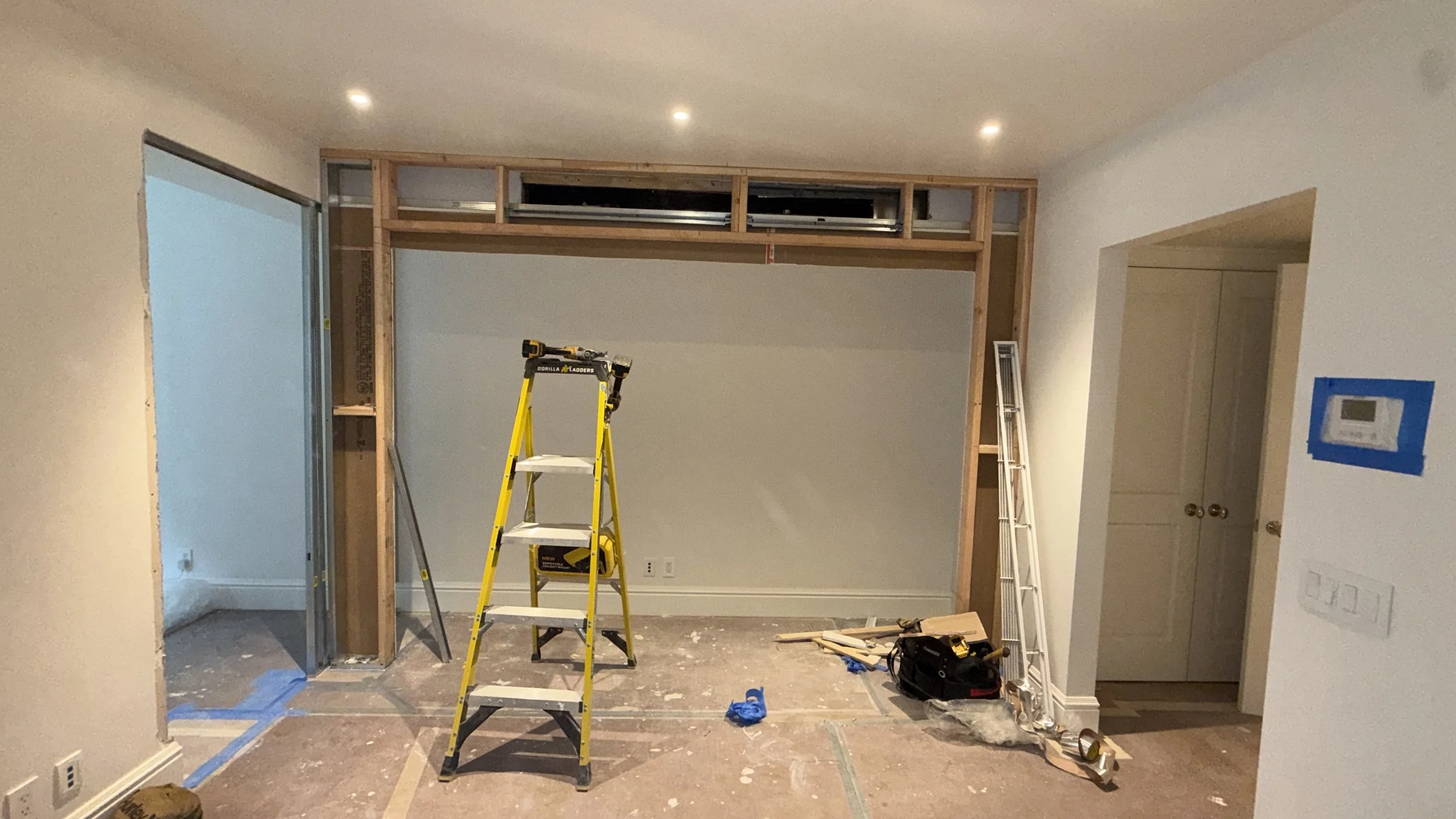 Interior of a room under construction with a ladder, tools, and framing in progress for a wall or doorway.