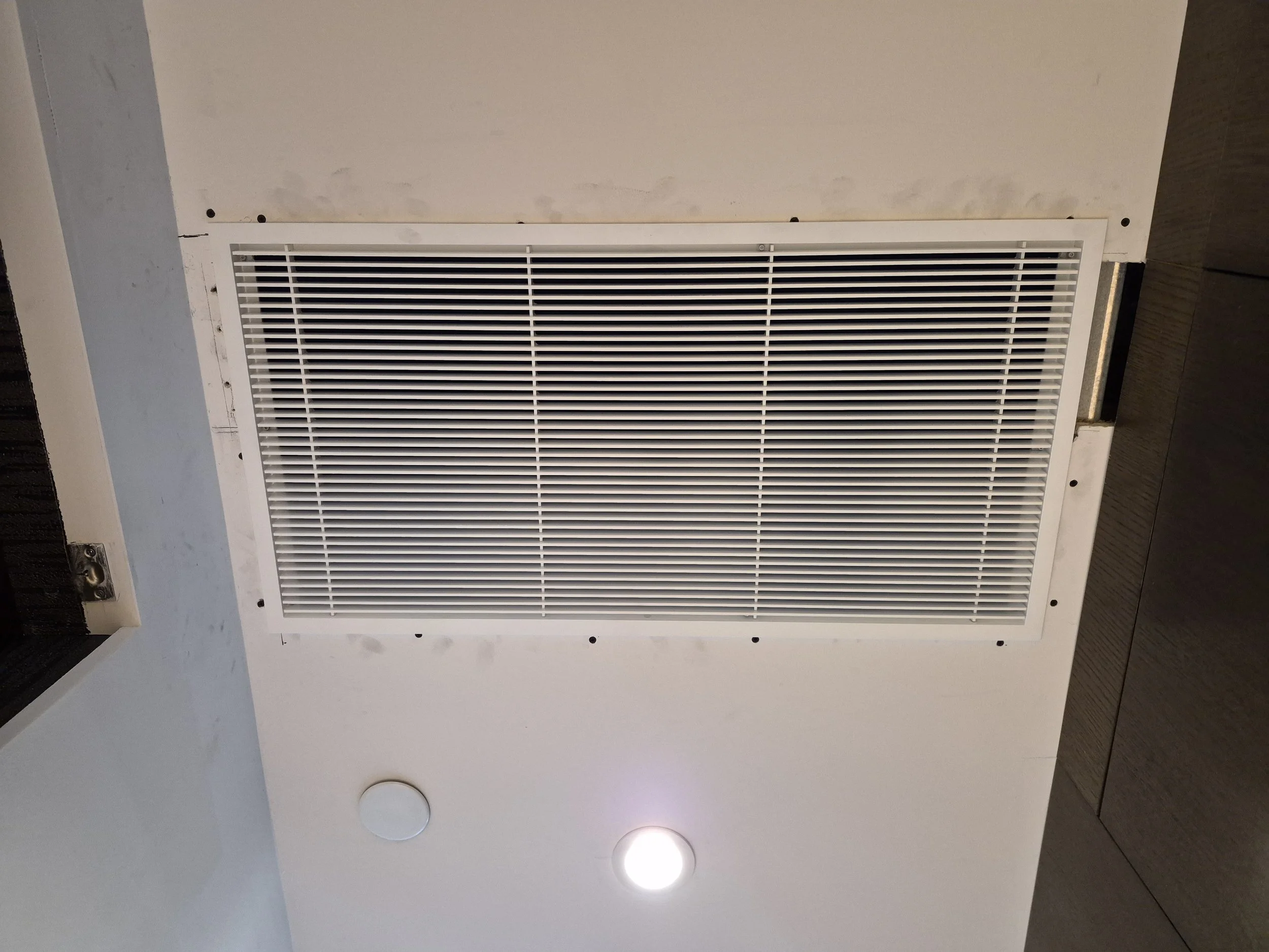 Ceiling with a vent and a recessed light fixture.