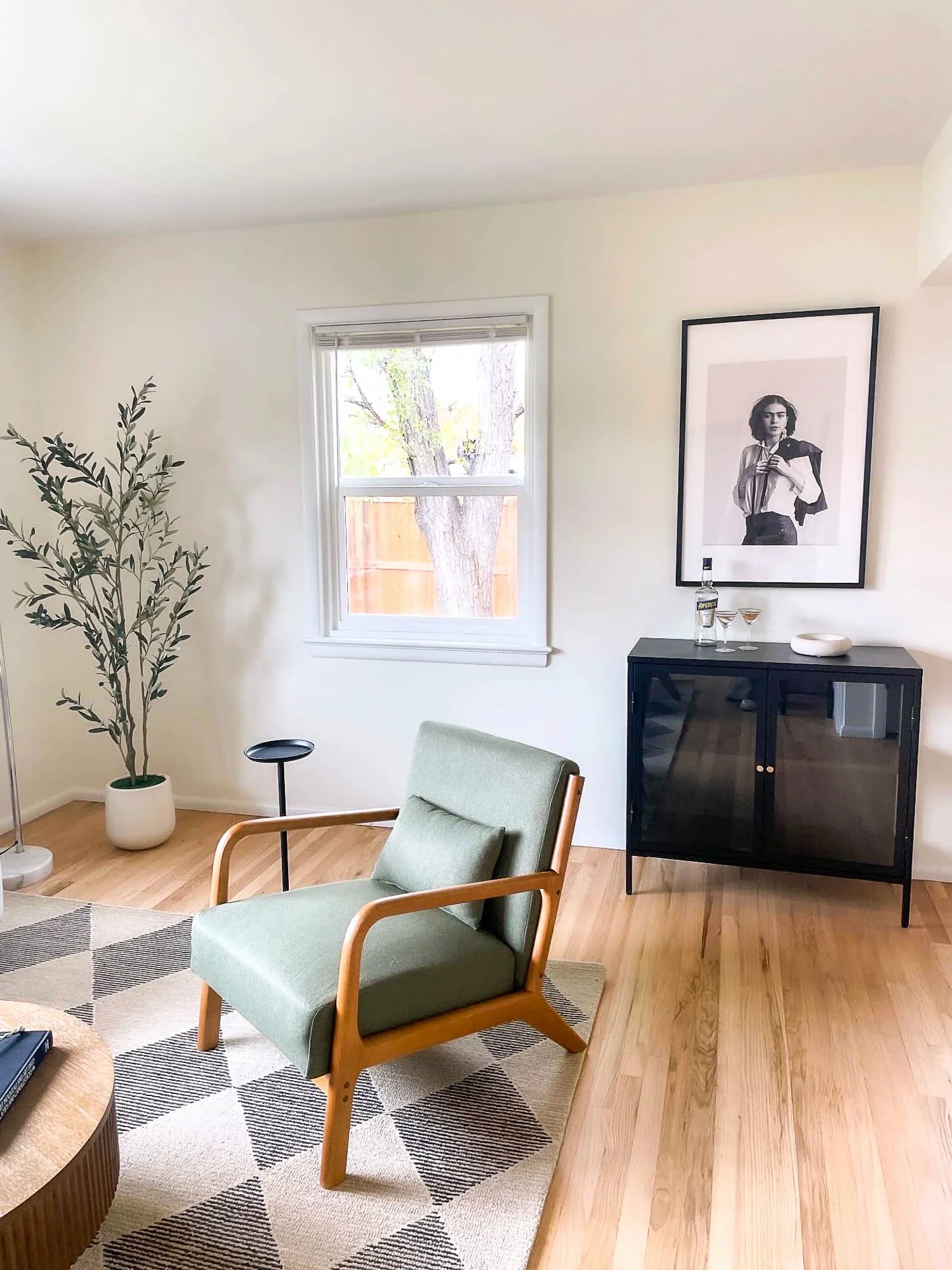 A sage green mid-century modern lounge chair with a credenza behind it.