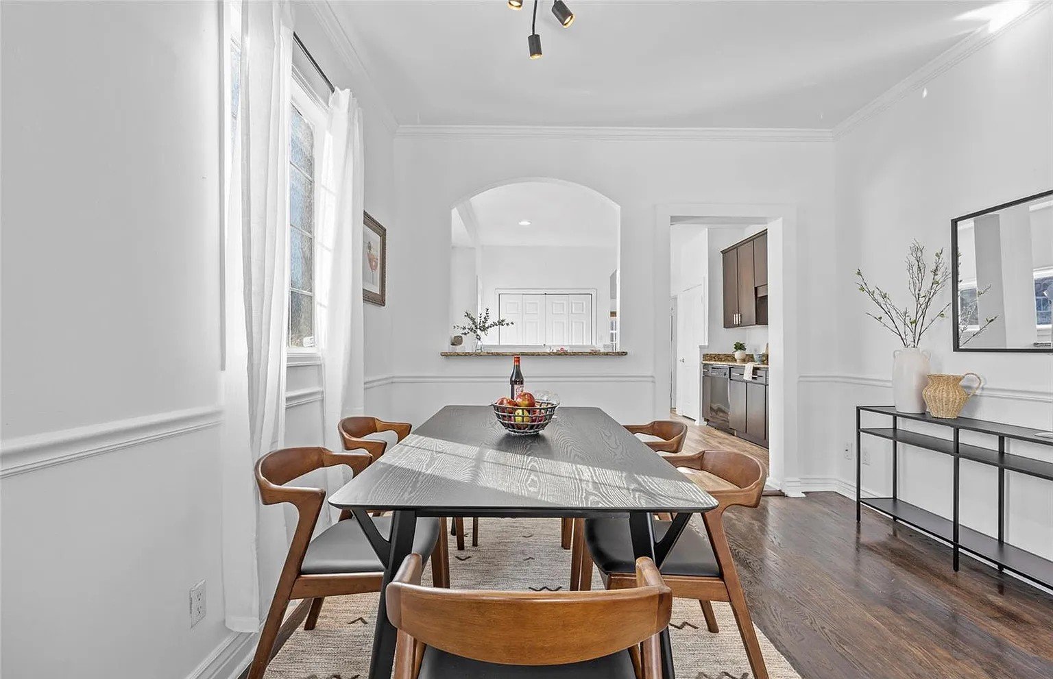A dining room with a black table and Scandinavian-style wooden dining chairs.