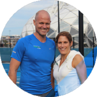 Man and woman smiling outdoors with a cityscape background.