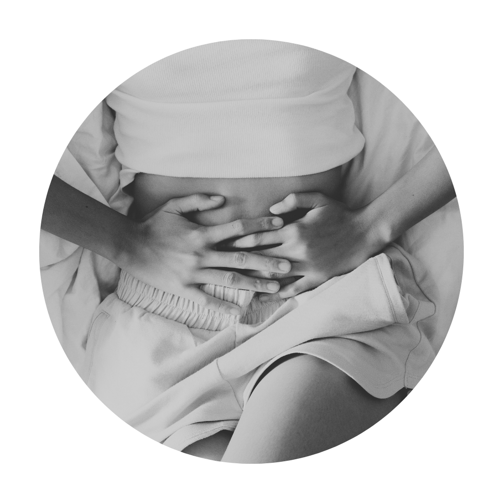 Person holding their stomach, wearing a white top and shorts, in black and white.