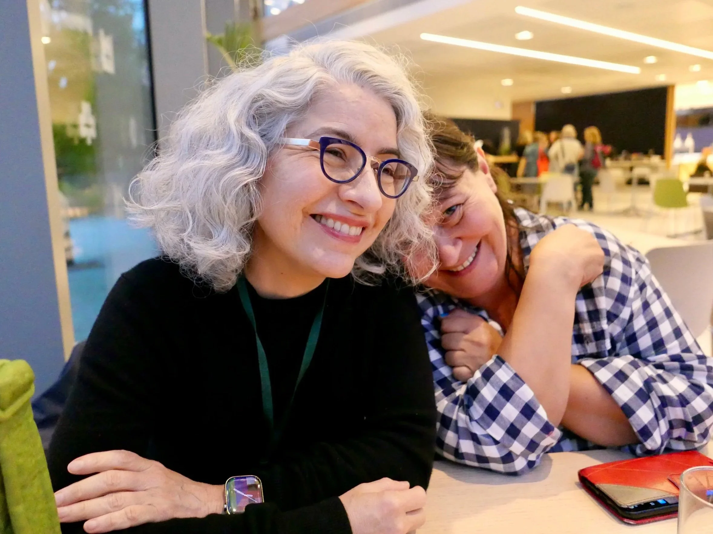 Rosella Buono and Jessica Santascoy laughing together at a table during the International Alexander Technique Congress at University College Dublin.