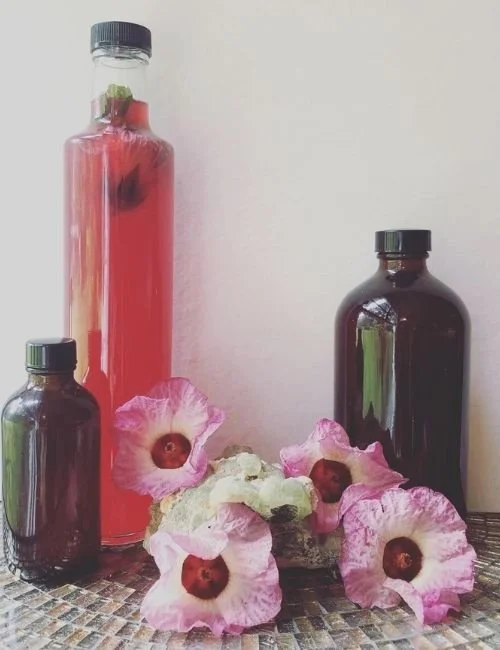 Three bottles of various sizes and a bunch of flowers