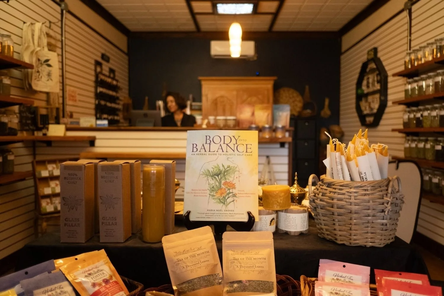 A table in the middle of a shop with displays of bags of teas, sprays, and a book called Body in Balance.