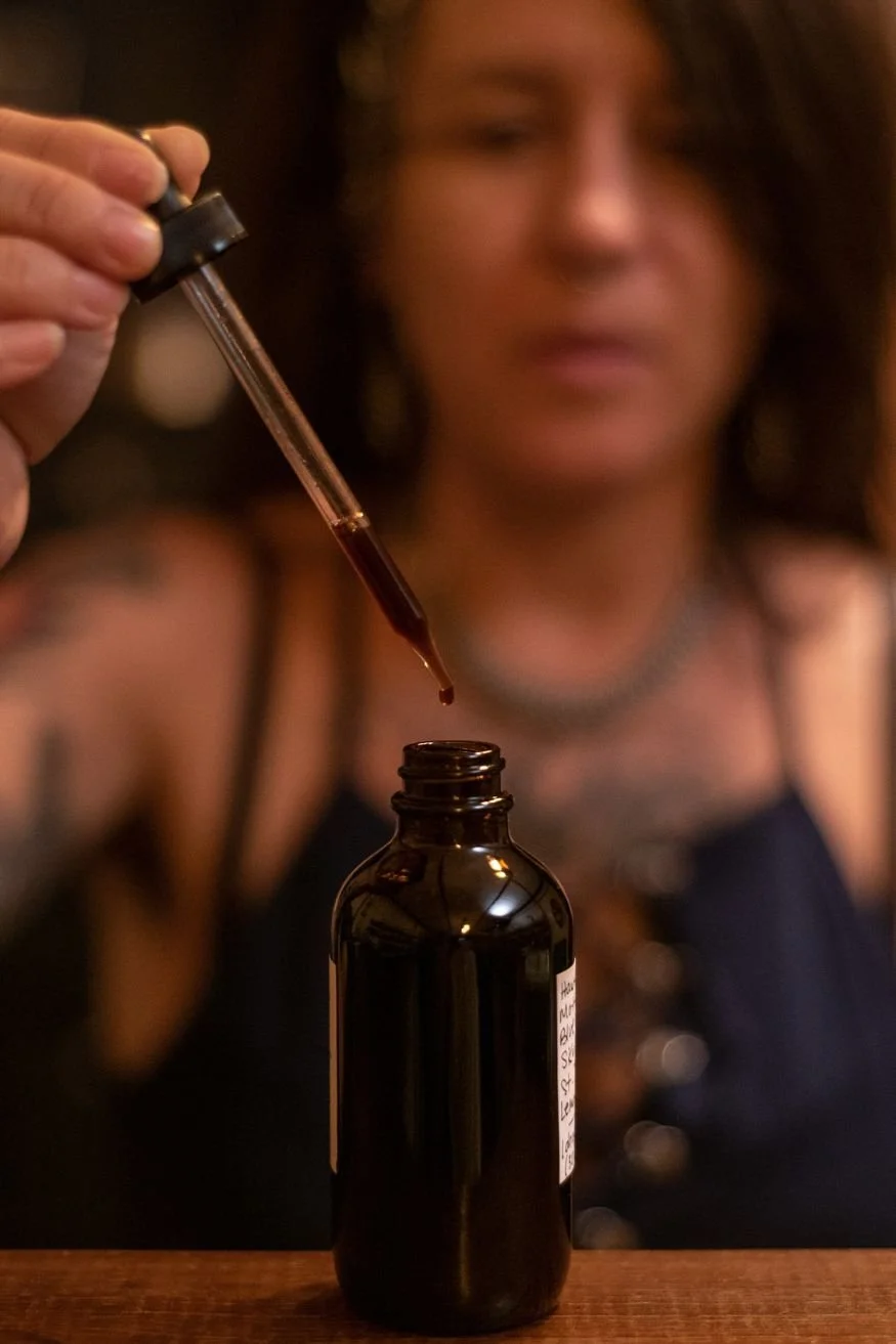 A close up of a small brown bottle and dropper with a person blurred in the background.