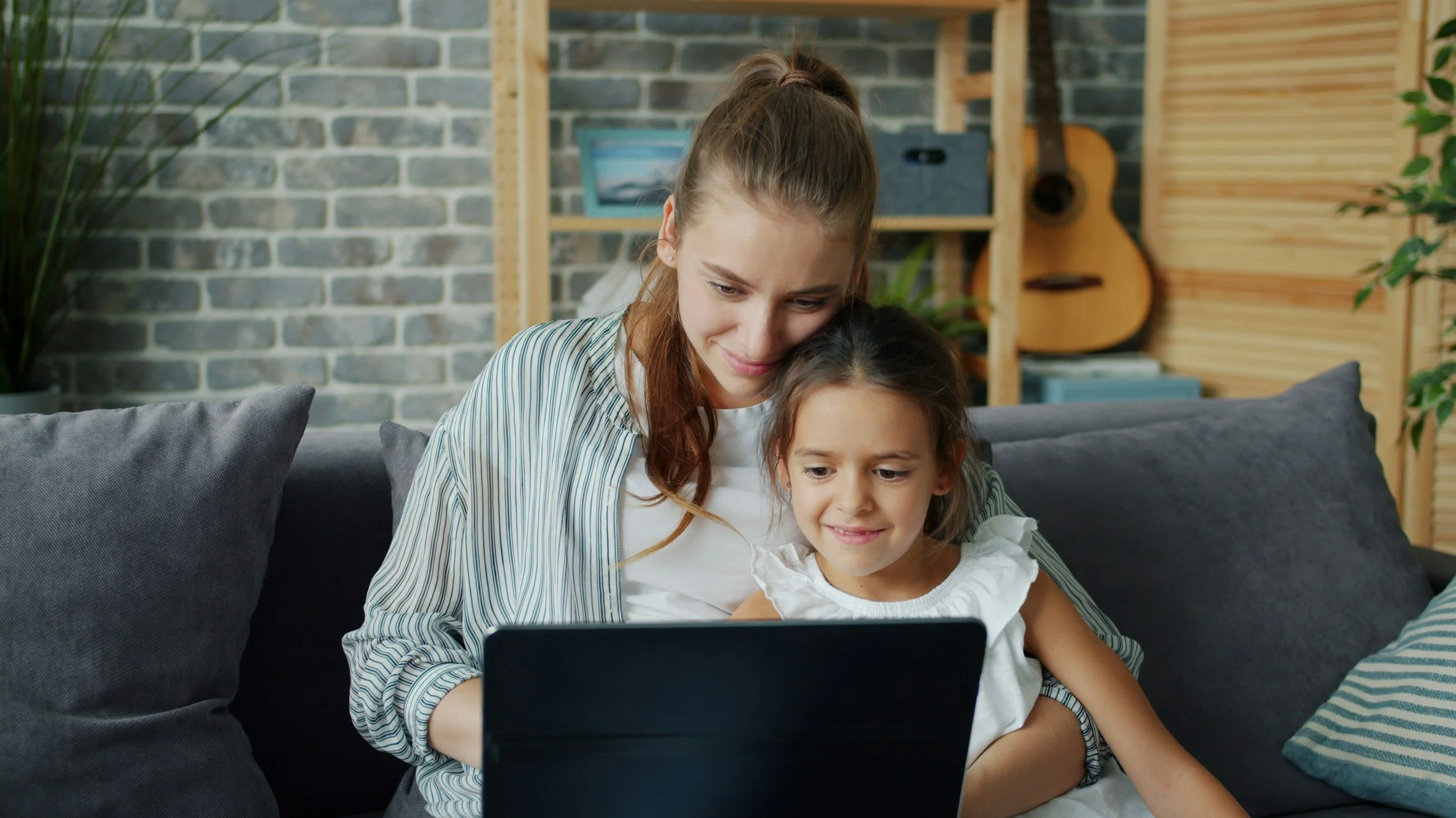 Mother and daughter watching a video together on a laptop, warm and cozy