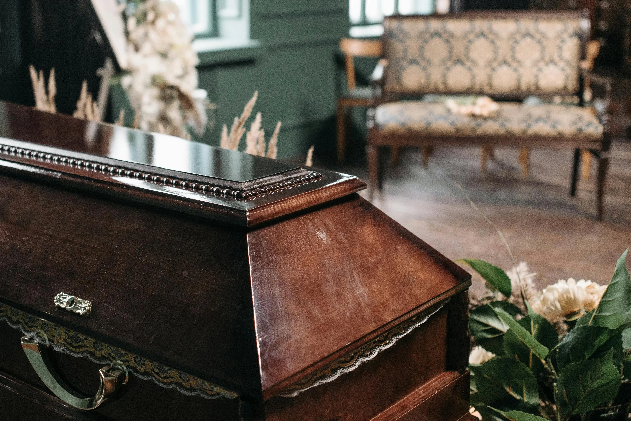 Close-up of a vintage wooden piano with flowers and a lace trim in a cozy, antique-style room.