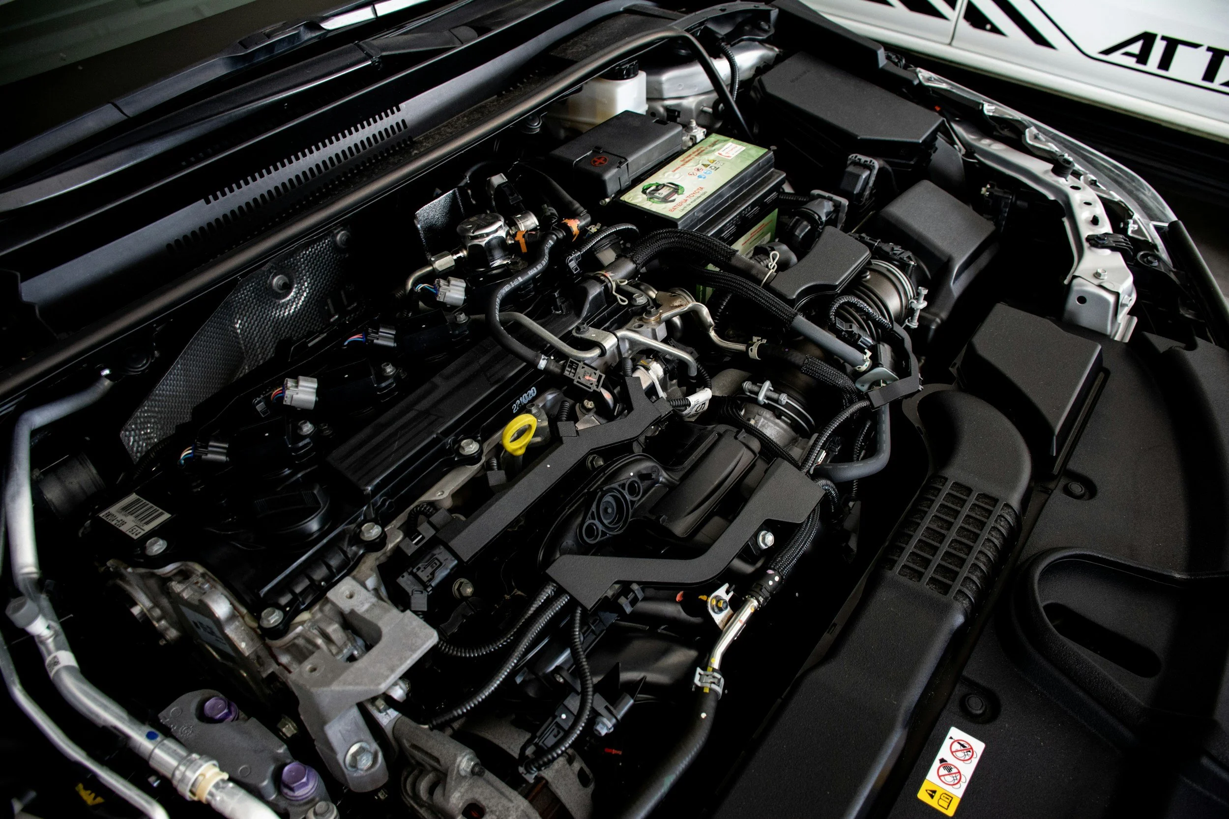 Close-up of a modern car engine with various metal and plastic components, hoses, and cables.