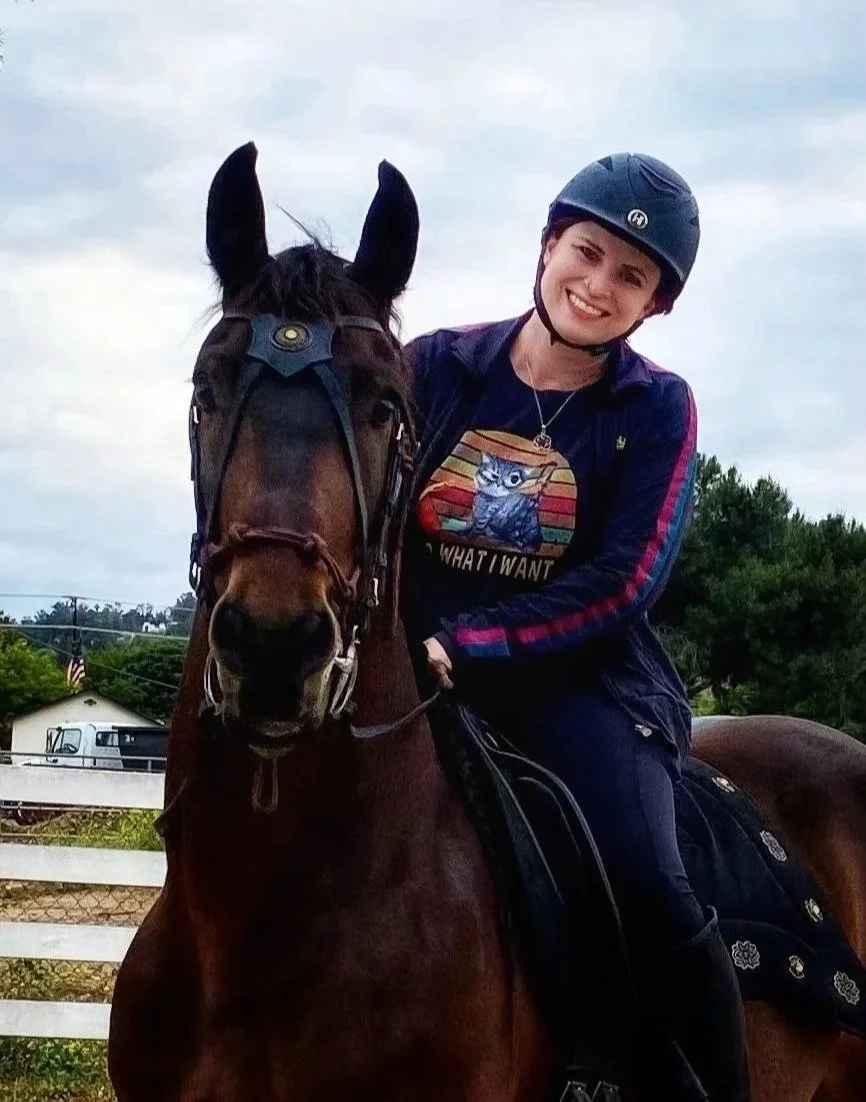 Marion Rhodes, executive copywriter and SEO strategist, riding a horse outdoors, smiling at the camera.