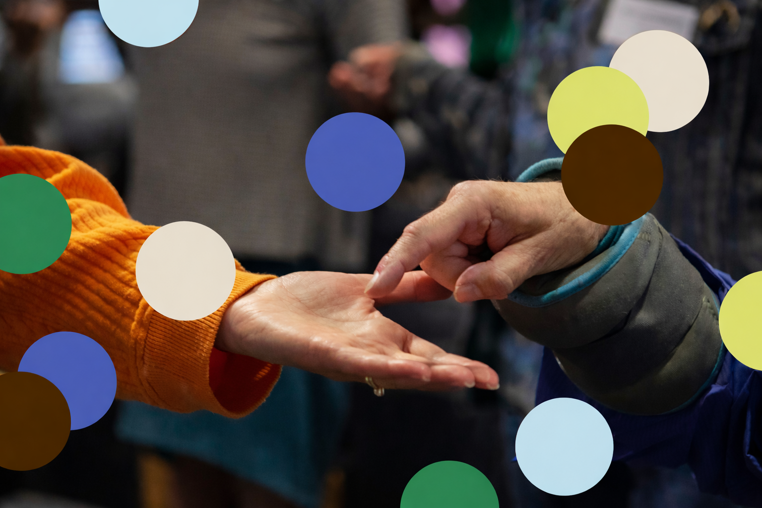 Two people touching fingertips in a gentle touch, one wearing an orange sleeve and the other a gray sleeve, in a closely engaged gesture.