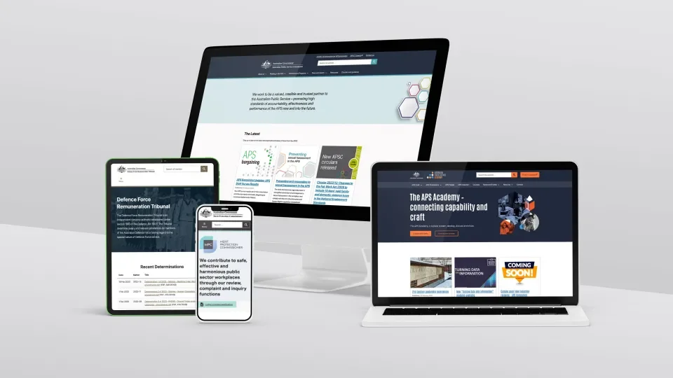 Multiple electronic devices including a desktop monitor, laptop, tablet, and smartphone displaying the website of the Australian Public Service (APS) Academy.