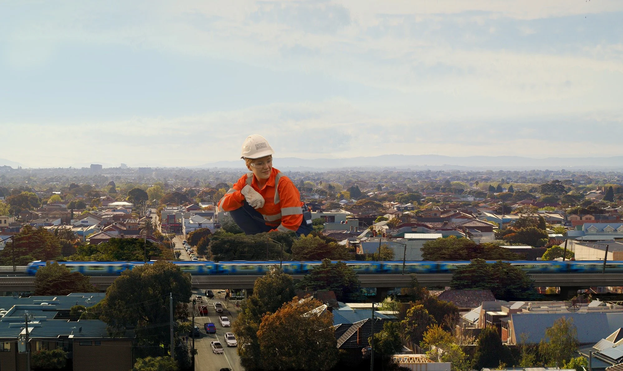 A woman in construction attire, including a white helmet and high-visibility orange jacket, superimposed over a cityscape with houses, a train, and trees under a partly cloudy sky.