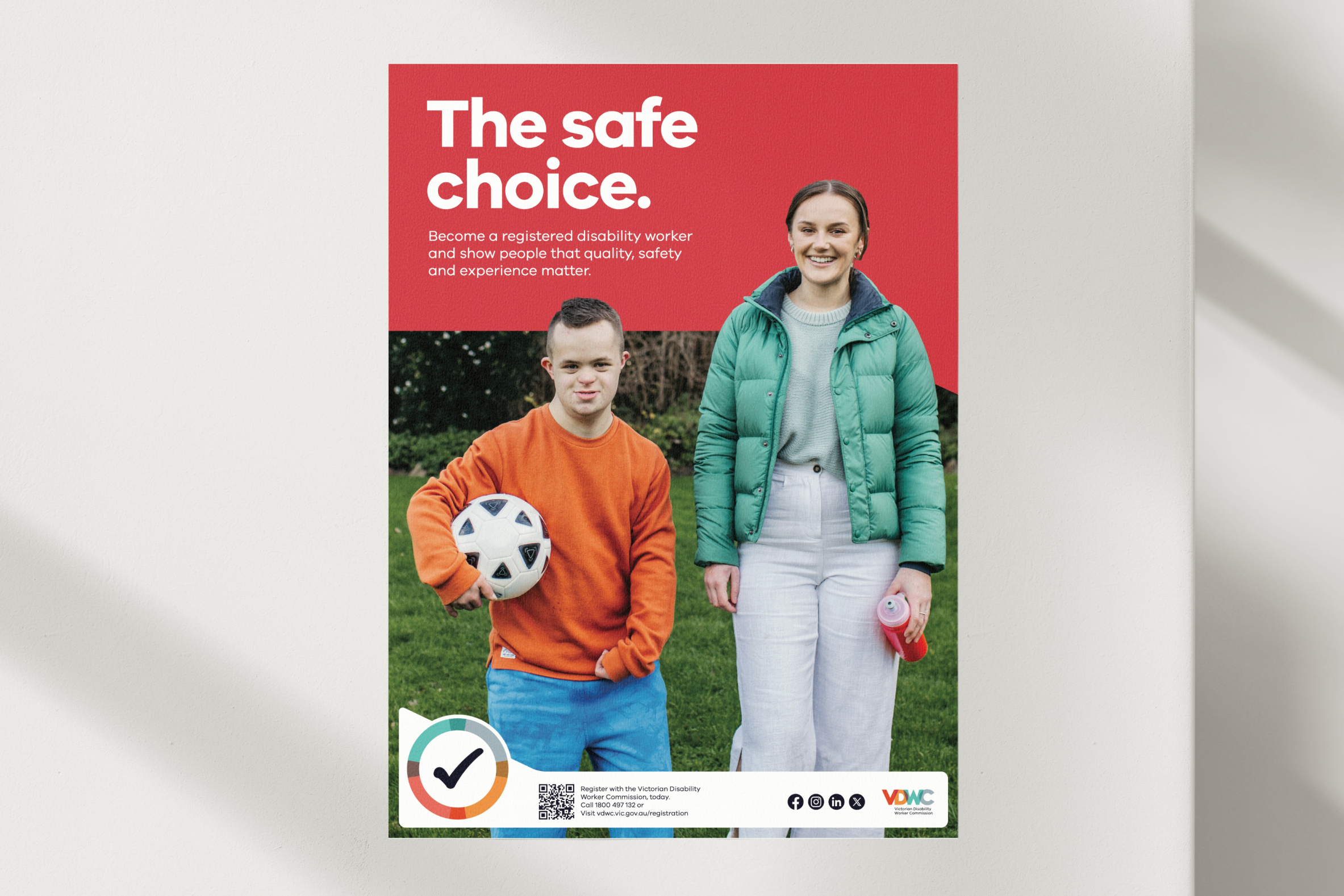 A poster with a red background and a photo of a smiling woman in a green jacket and a young man in an orange sweater holding a soccer ball. The text reads, 'The safe choice. Become a registered disability worker and show people that quality, safety, and experience matter.'