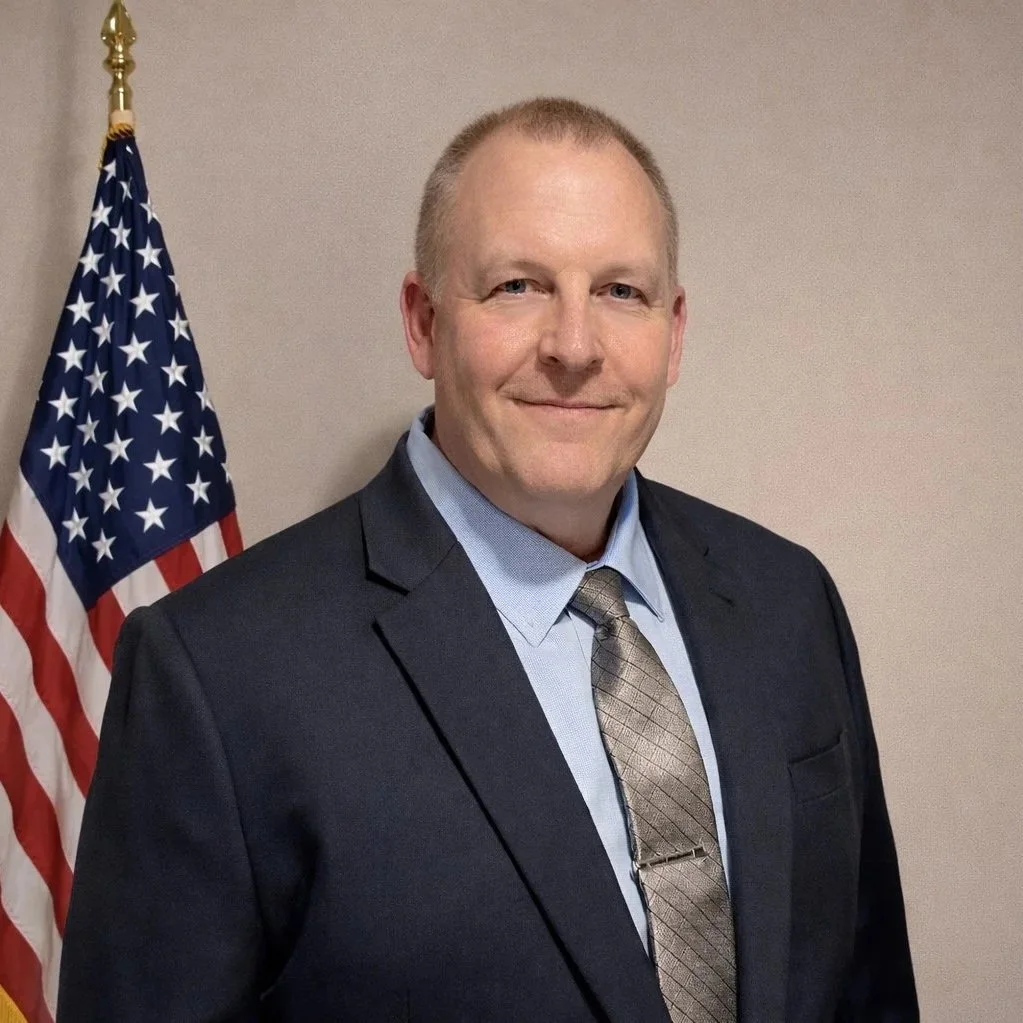 Don Burrows in a dark suit with a flag seen behind him