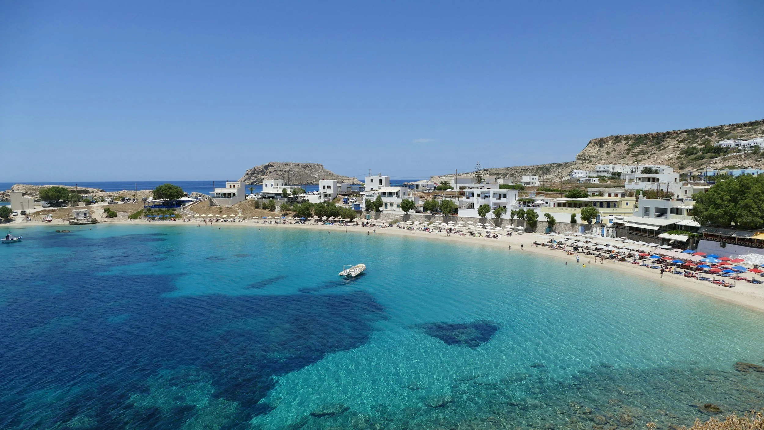 Turquoise water and whitewashed buildings along Lefkos Beach on Karpathos, Greece.