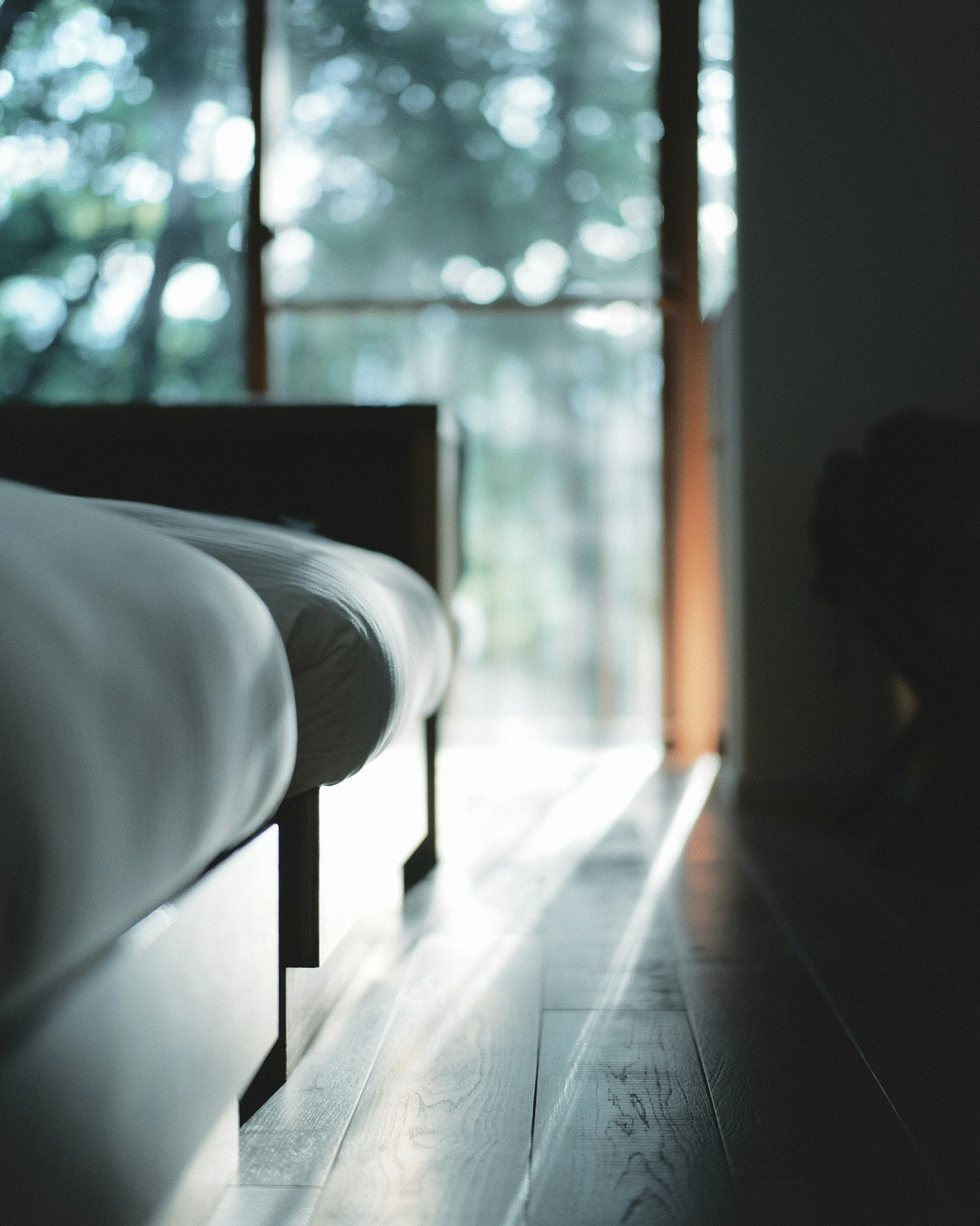 Peaceful guest room with soft natural light and views through large windows.