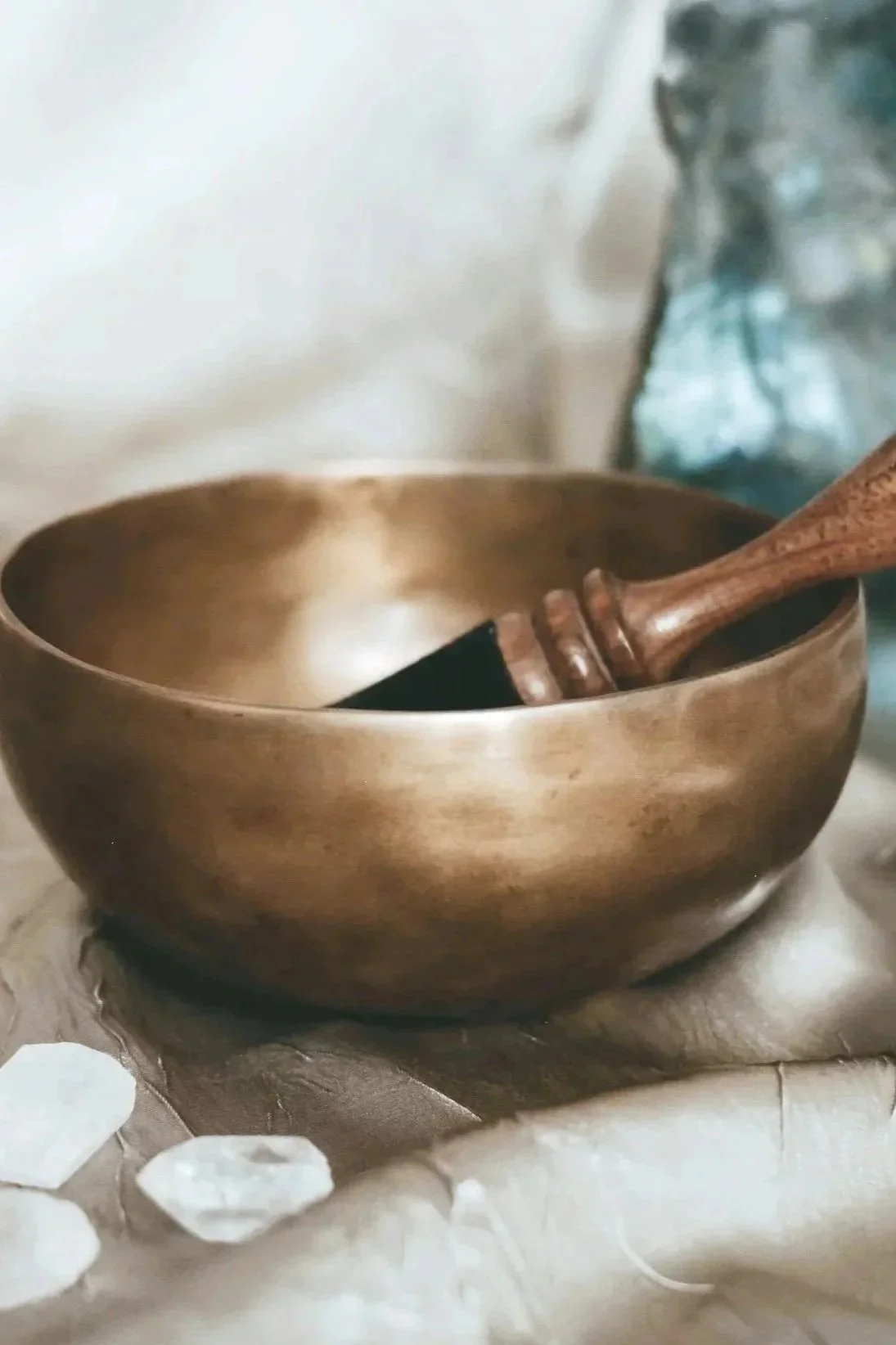 Brass singing bowl with white stones arranged for a sound healing practice.