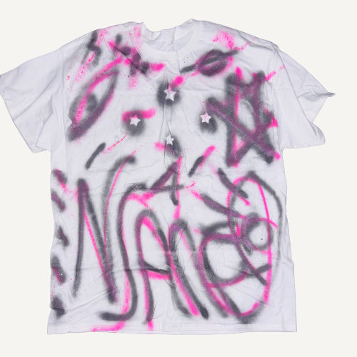 White T-shirt with pink and black spray paint graffiti and stars.