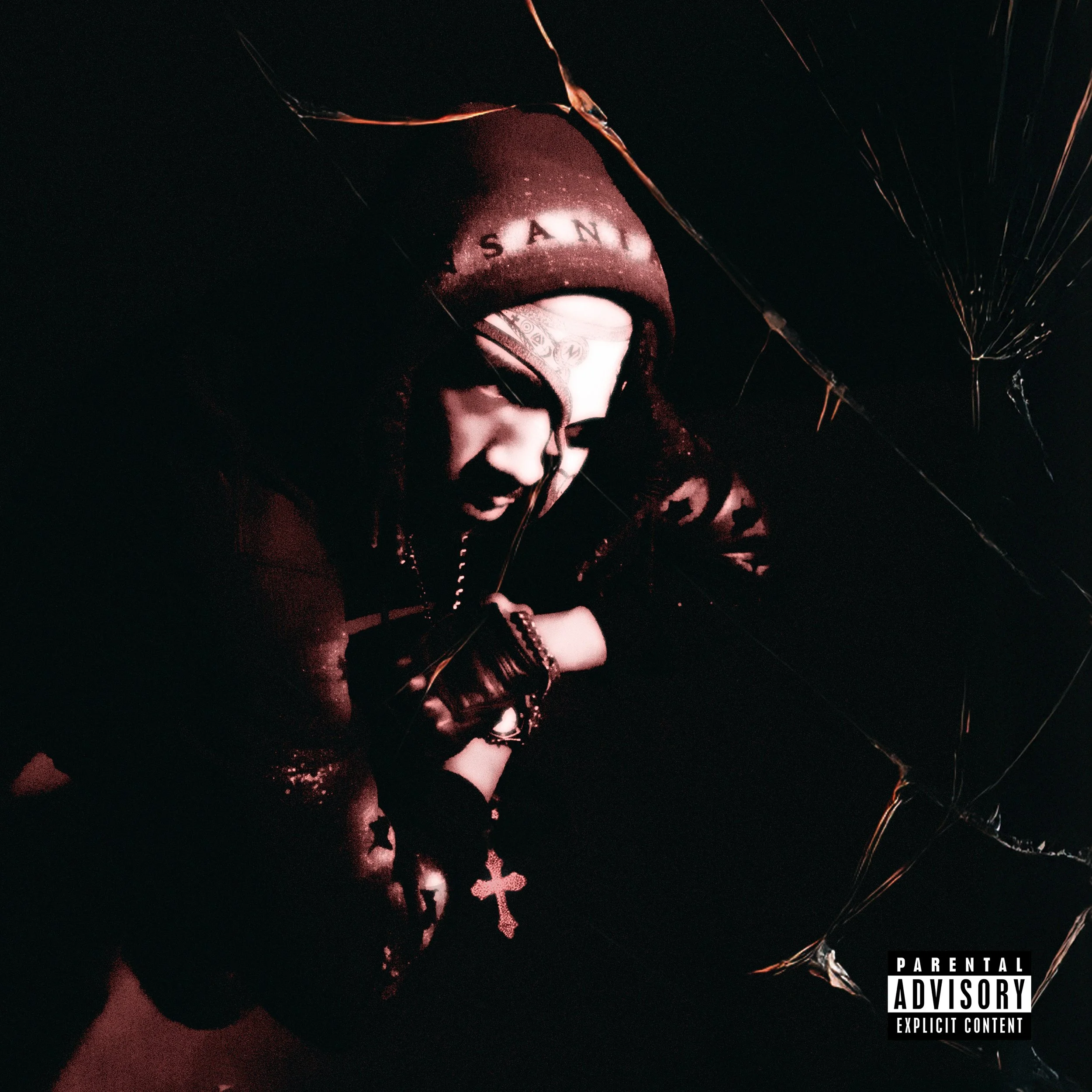 A person with a beanie and hoodie looking down, holding a cross necklace, with a dark background and cracked glass effect, with a parental advisory label on the bottom right.
