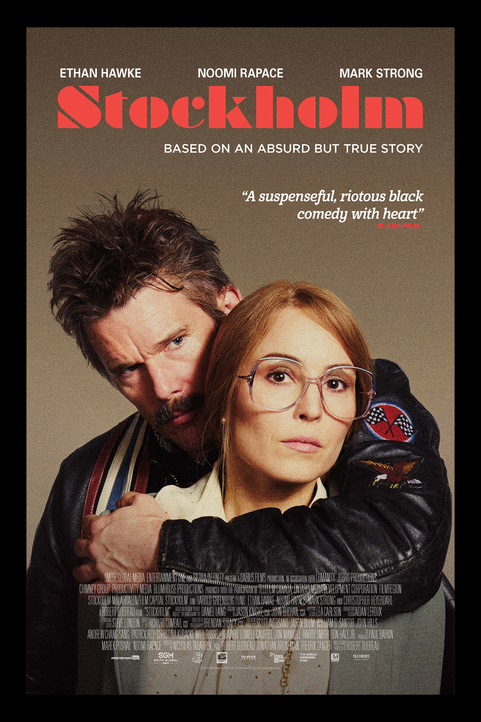 A movie poster for 'Stockholm' featuring Ethan Hawke and Noomi Rapace. Ethan Hawke is behind Noomi Rapace, hugging her and looking intensely at the camera. Noomi Rapace is wearing glasses and has a neutral expression. The background is gray, with the title in large red letters and various text elements.