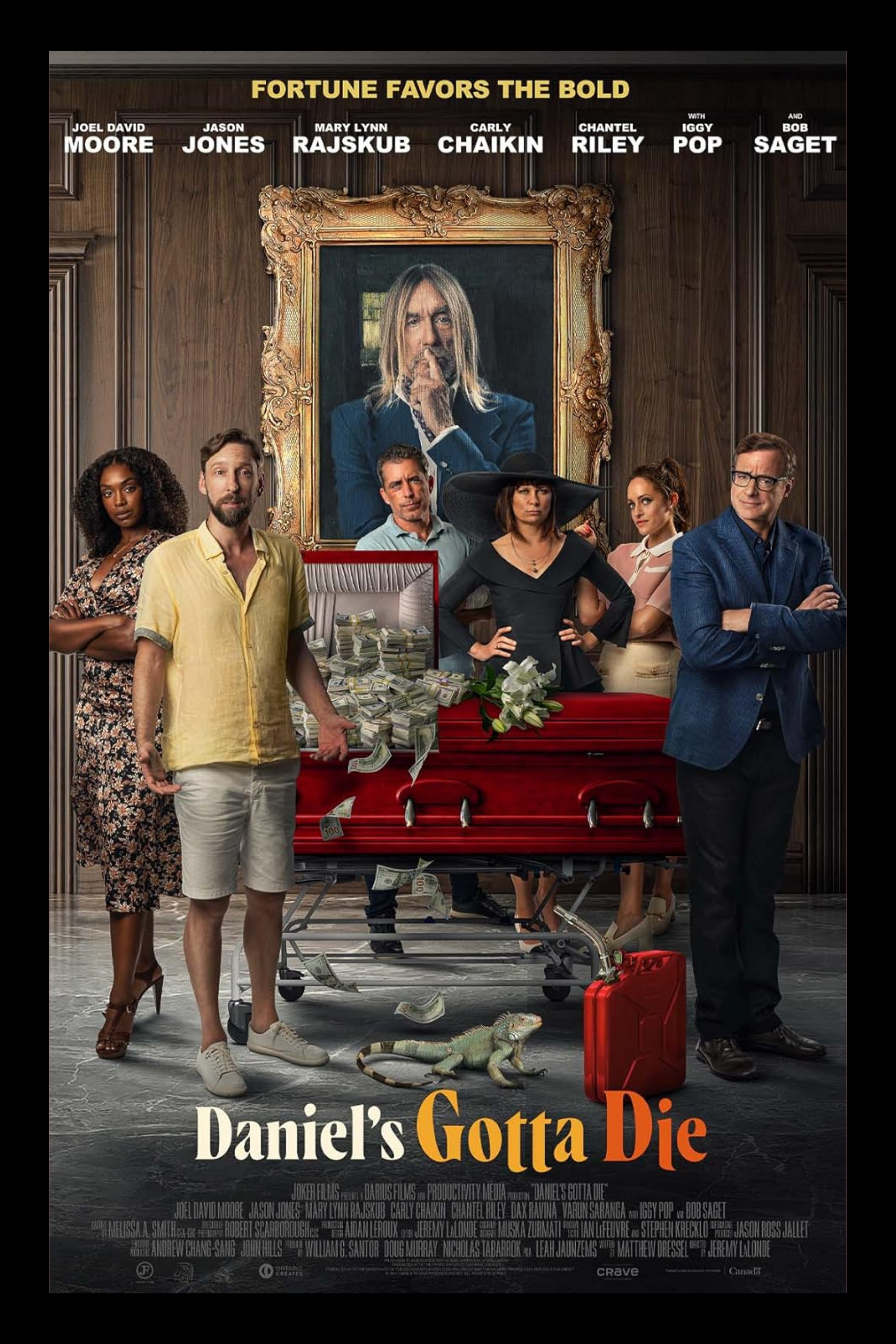 Group of seven people dressed in formal and casual attire standing around a red coffin with money scattered around it, inside a wood-paneled room with a large framed portrait of a man with long blonde hair in the background. A small lizard and a red gasoline can are on the floor.