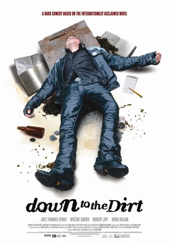 Person lying on the ground surrounded by books, a notebook, a bottle, and dirt, with the title "Down to the Dirt" and the tagline "A dark comedy based on the internationally acclaimed novel" above.