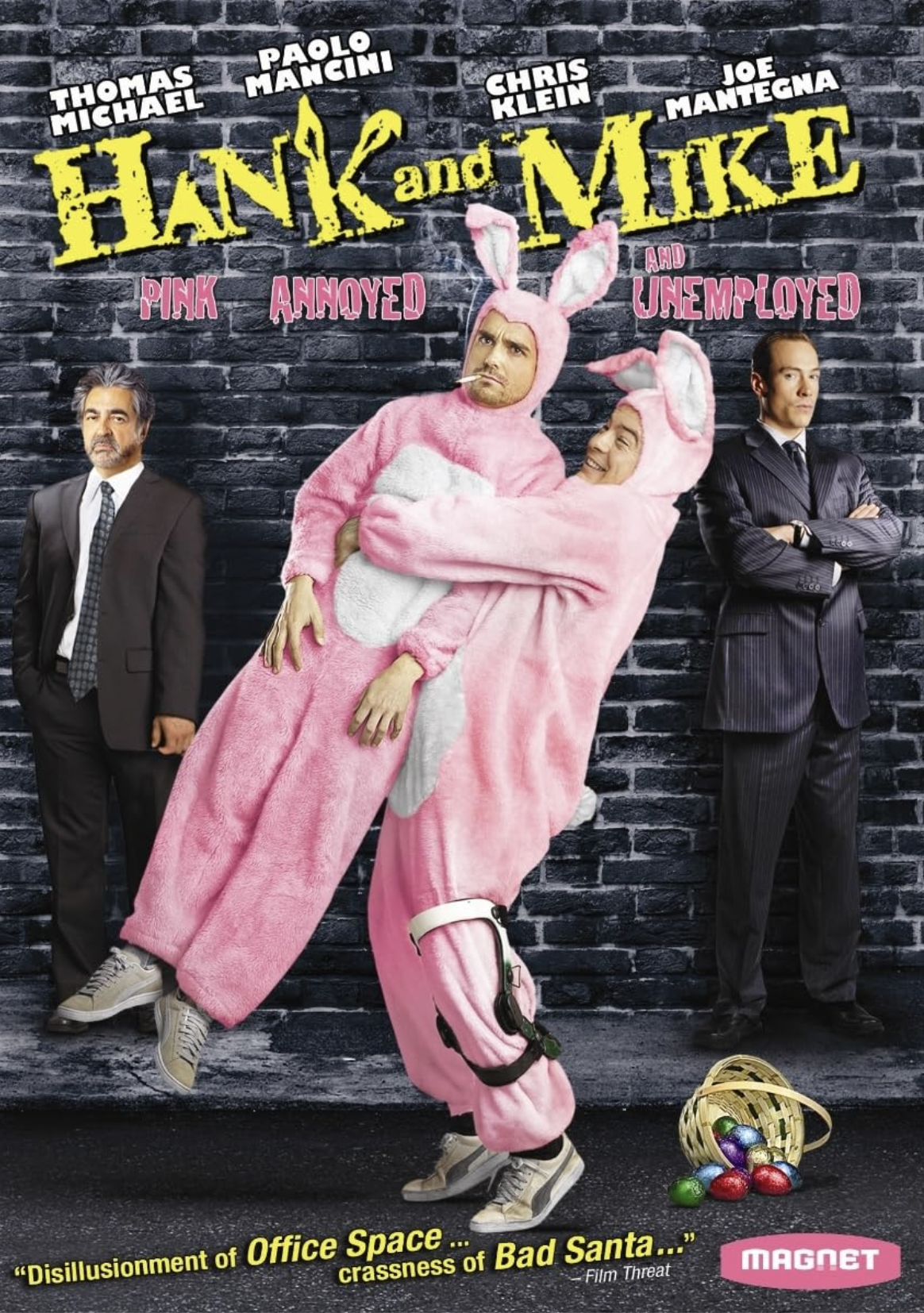 Movie poster for "Hank and Mike" featuring two men in pink bunny costumes hugging, with one man wearing a straight face and the other smiling. Two men in suits stand on either side against a brick wall background, with a basket of colorful Easter eggs at the bottom right.