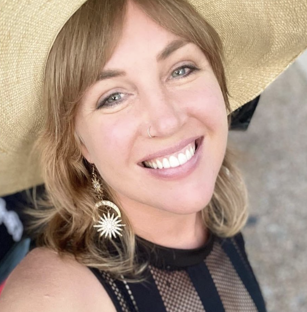Alison wearing a wide-brimmed hat and sunburst earrings.