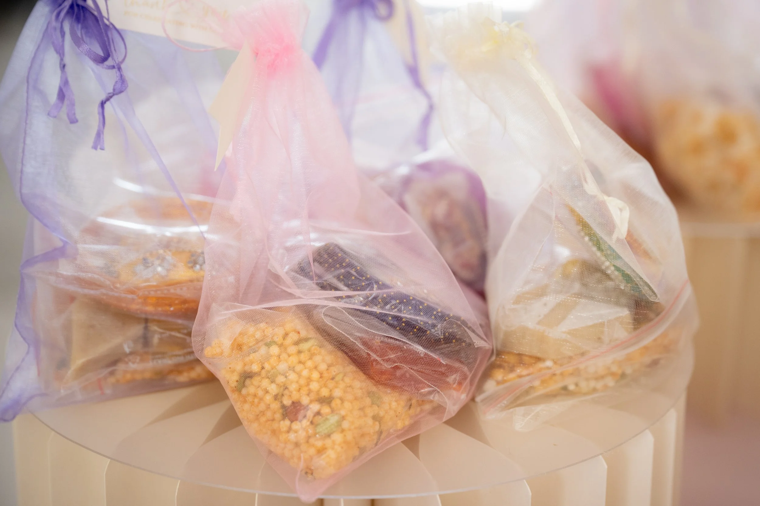 Multiple small plastic bags filled with colorful sprinkles and candy toppings, placed on a white surface.