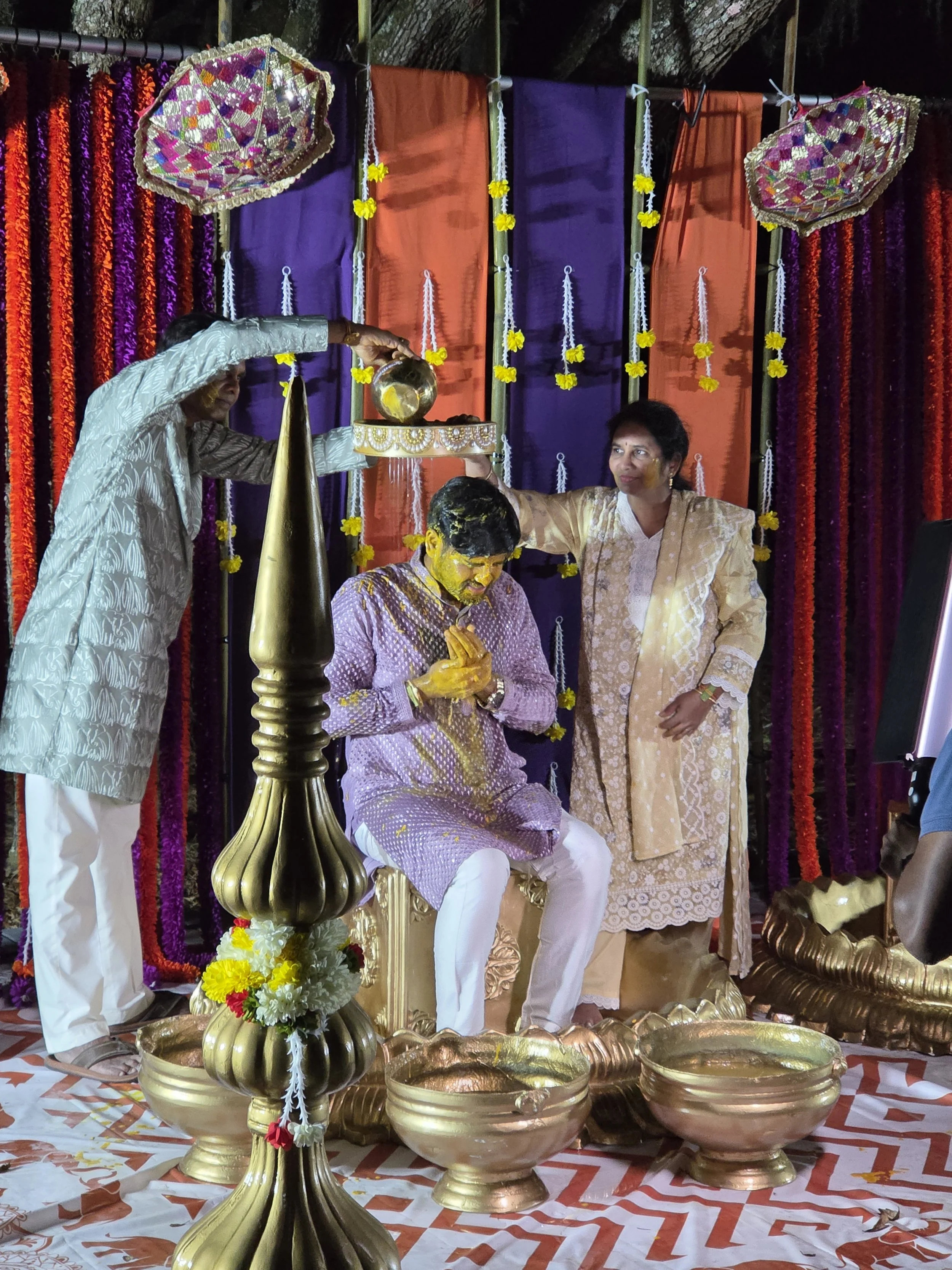 People participating in a traditional Indian wedding ceremony with decorations, flowers, and ceremonial objects.