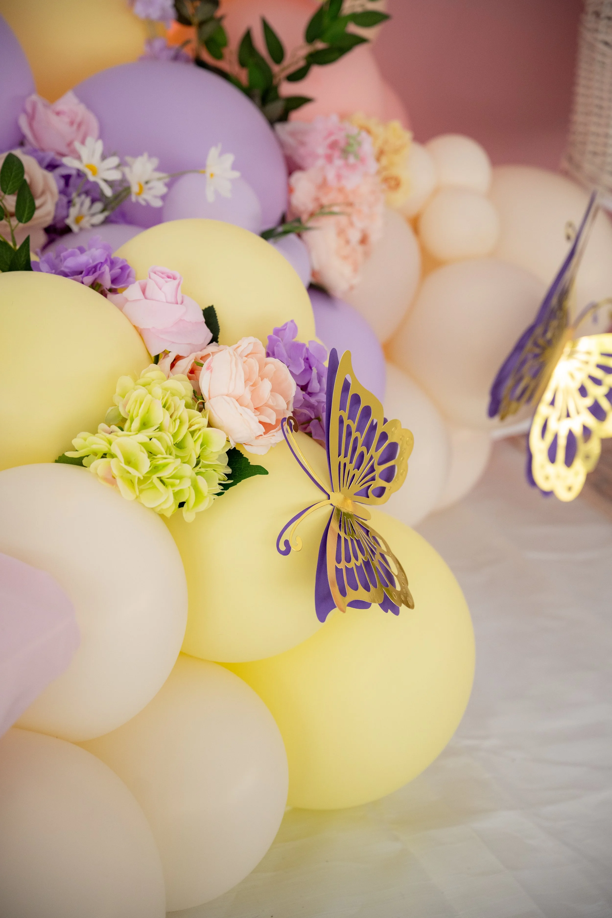 Colorful balloons decorated with flowers and butterfly cutouts at a celebration or party.