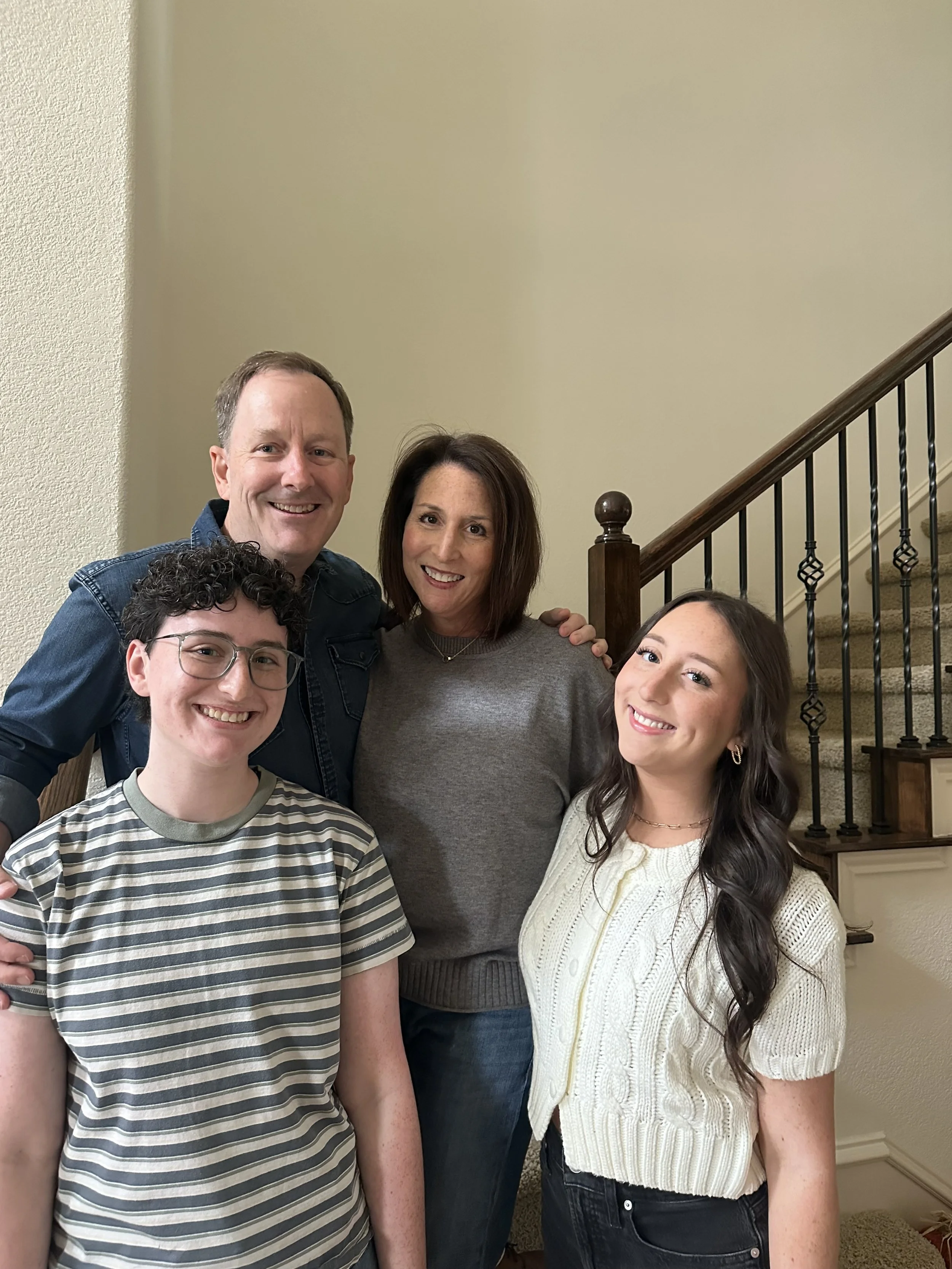 A family of five posing on a staircase inside a home, smiling at the camera.