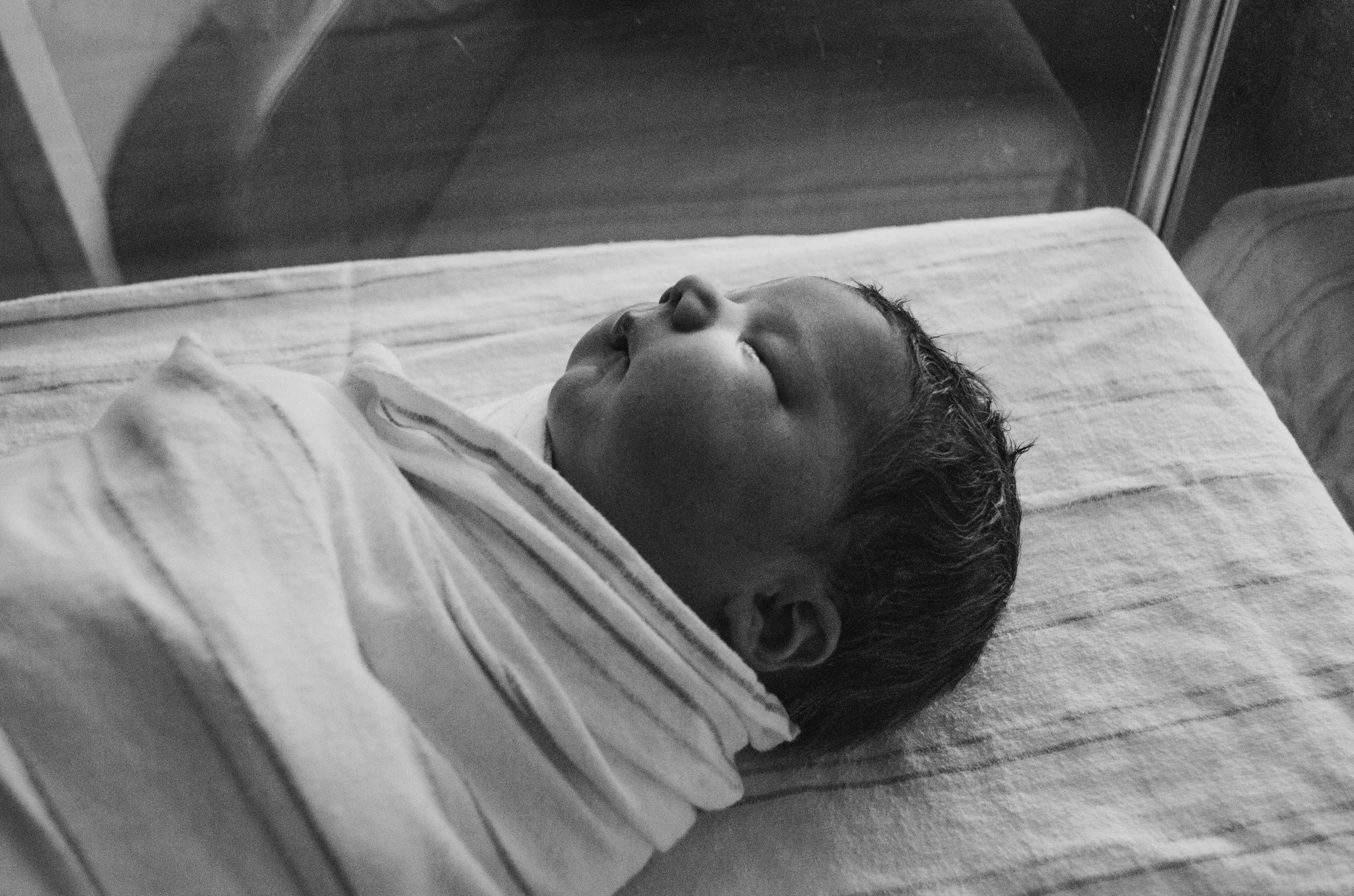 Black and white photo of a newborn baby sleeping on a pillow.