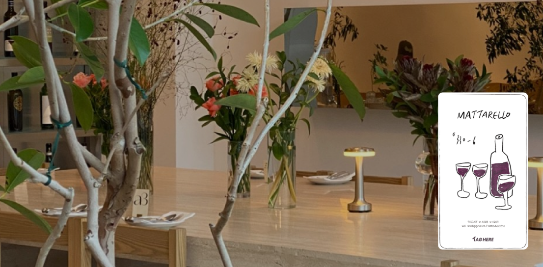 A dining table decorated with vases of flowers and a table number, set for a meal with plates, cutlery, and small candles.