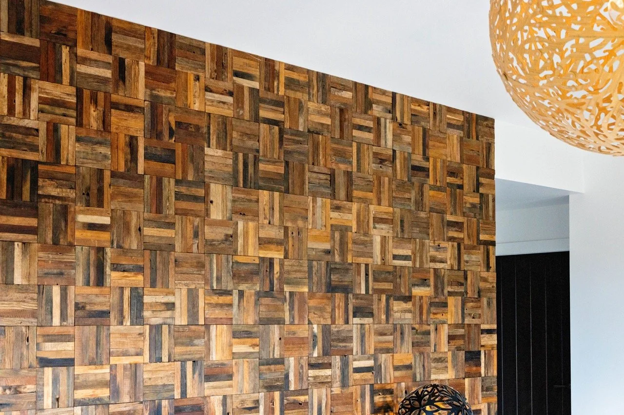 Interior view of a modern room with a wooden panel accent wall, a black decorative object, and a large orange woven pendant light.
